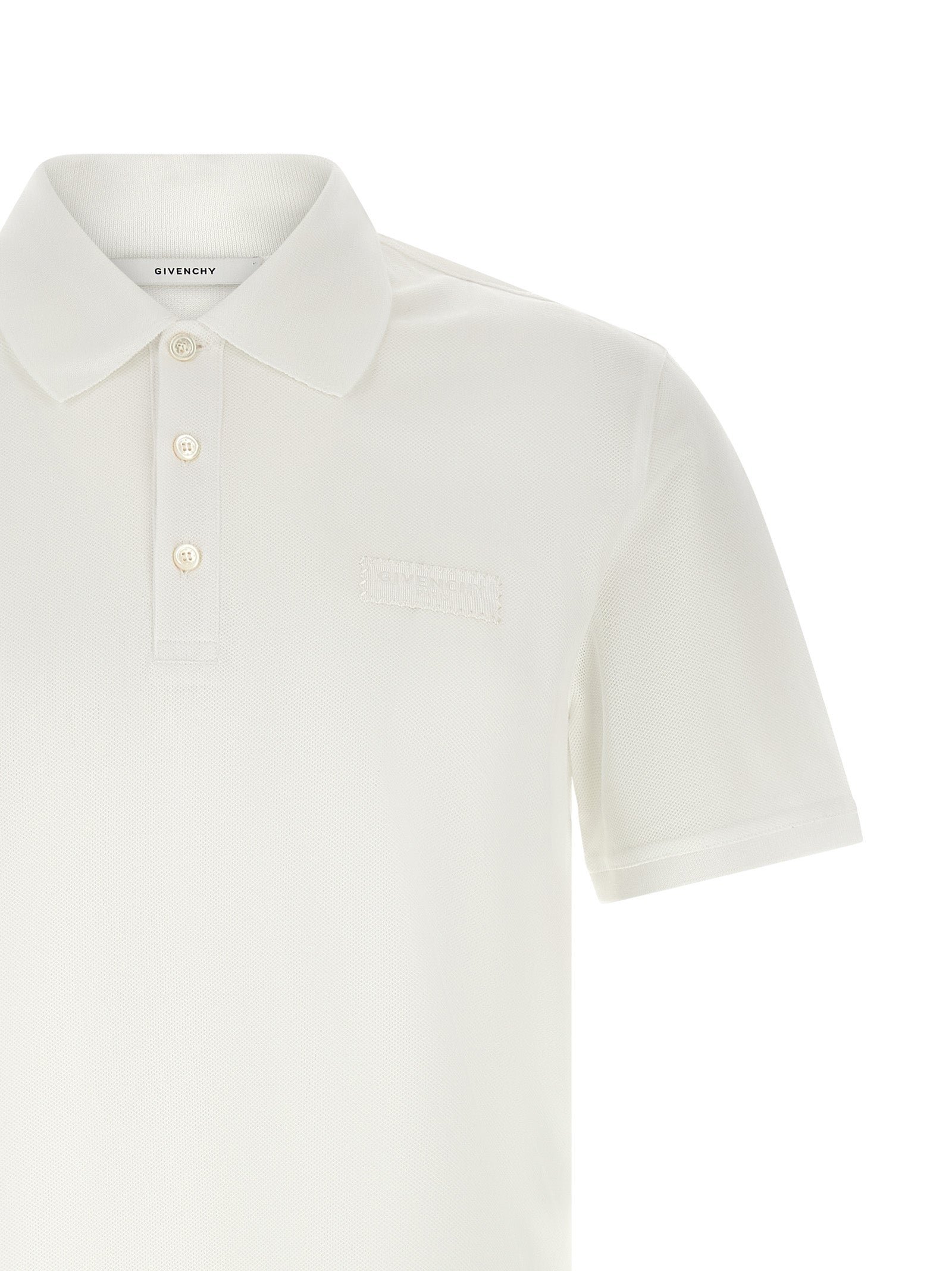 Chemise polo en coton blanc de Givenchy, avec col classique et logo discret, sur un fond neutre.