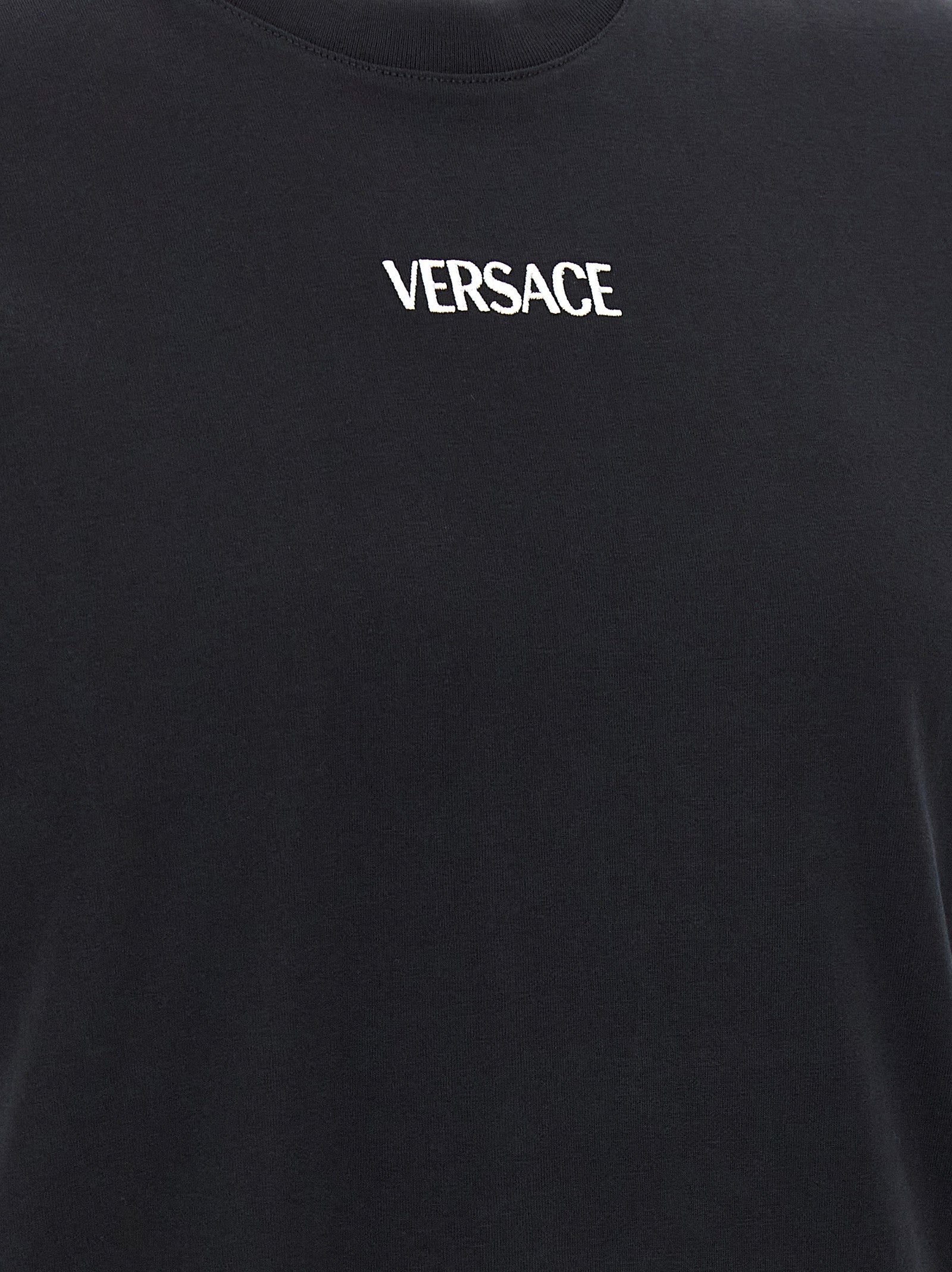 T-shirt en coton noir de la marque Versace avec logo emblématique, porté sur un mannequin.