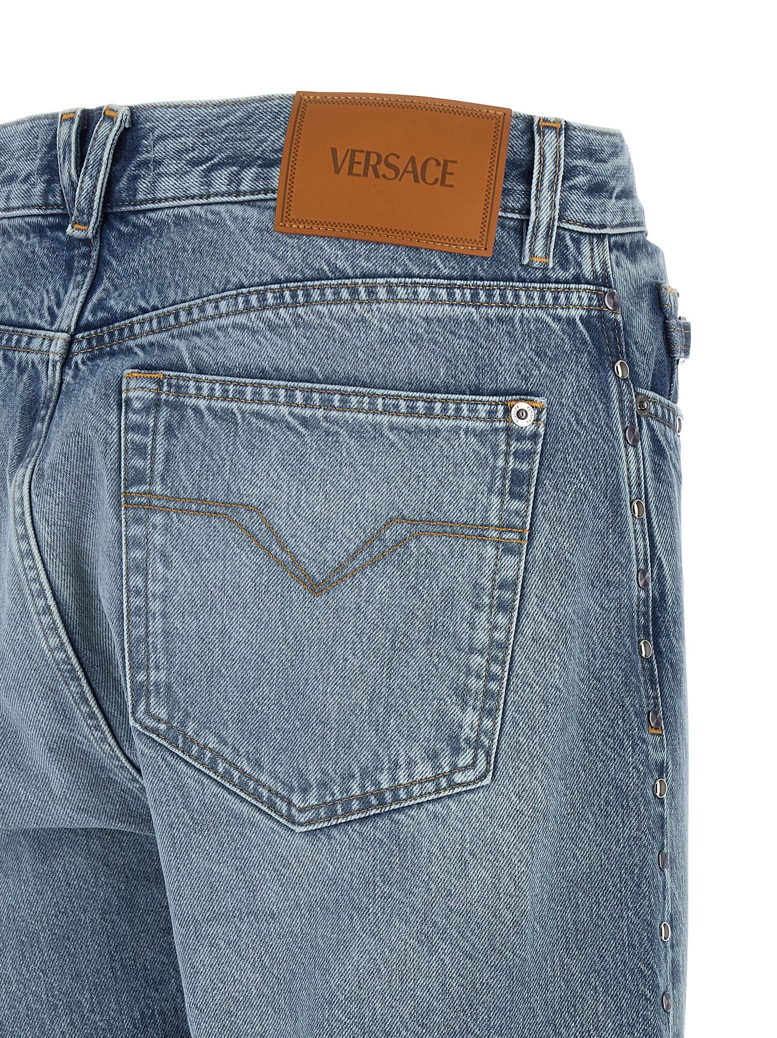 Jeans droits en coton bleu de la marque Versace, vue devant avec détails de la coupe droite et la texture du tissu.