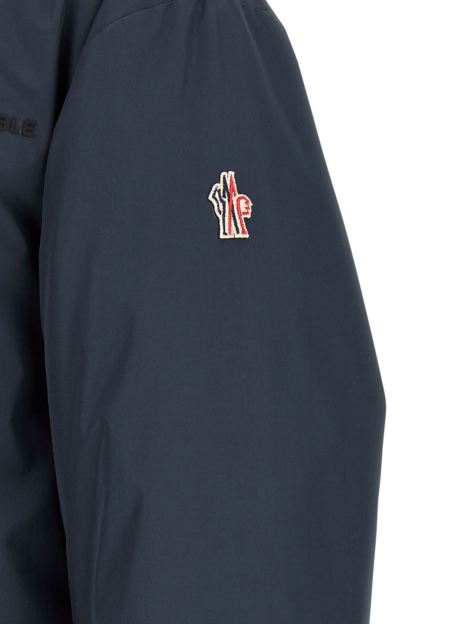 Veste Moncler Grenoble en polyamide bleu, coupe-vent et résistante, avec capuche et fermeture zippée.