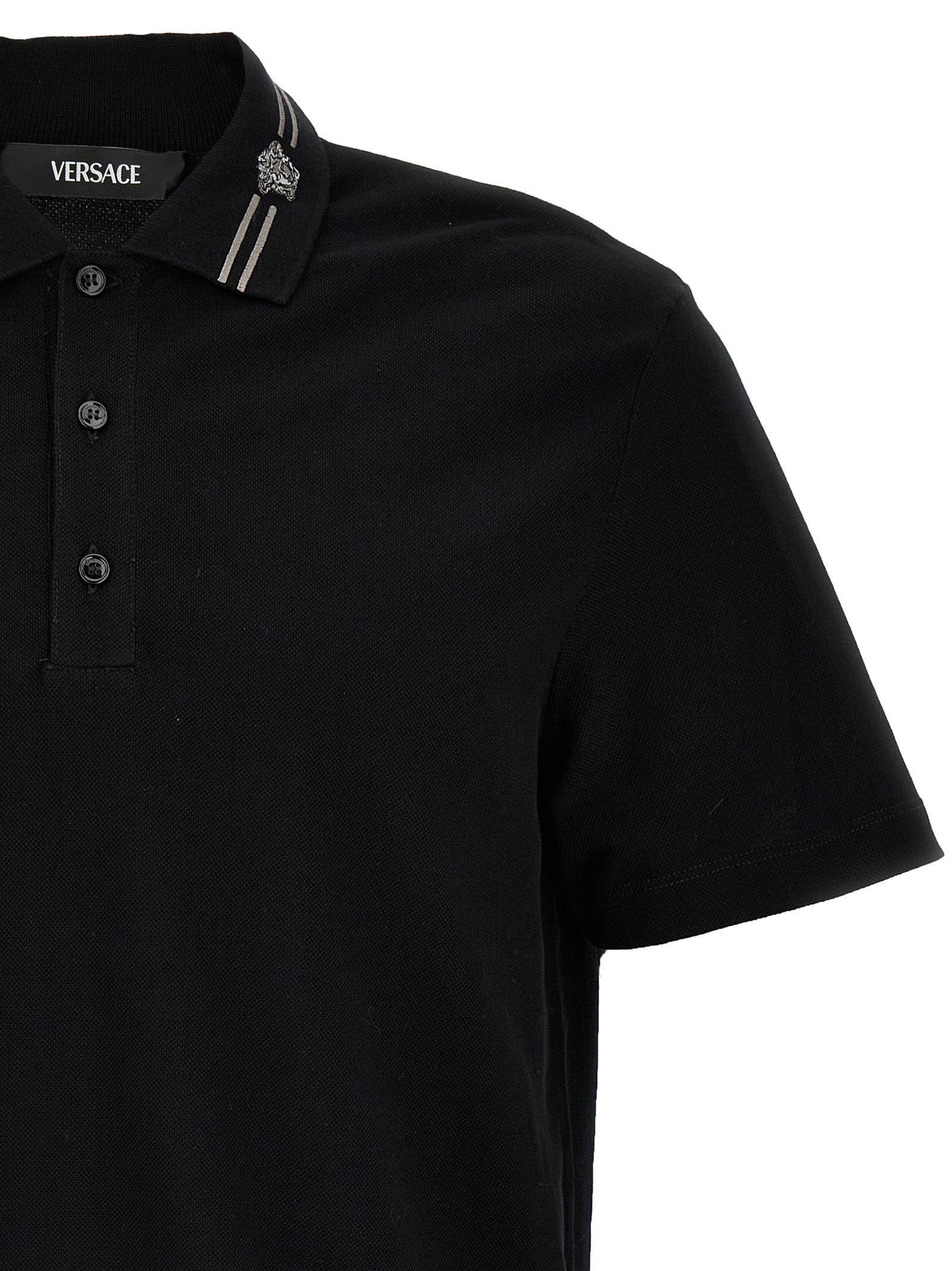 Chemise polo en coton noir de la marque Versace, avec détails élégants et logo distinctif visible sur le devant.