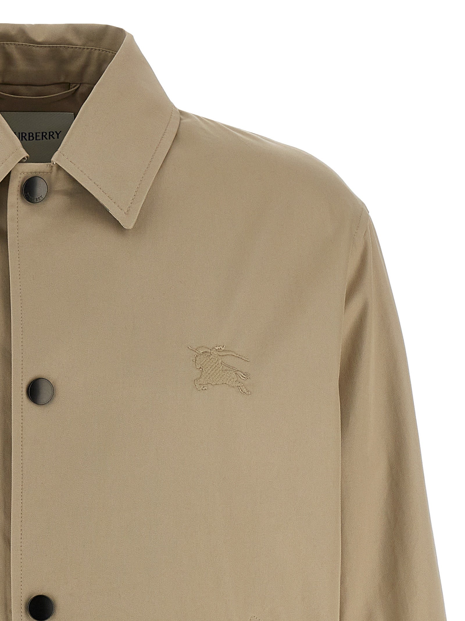 Veste en coton beige Burberry, coupe longue et élégante, avec détails classiques et finition soignée visible sur l'image.