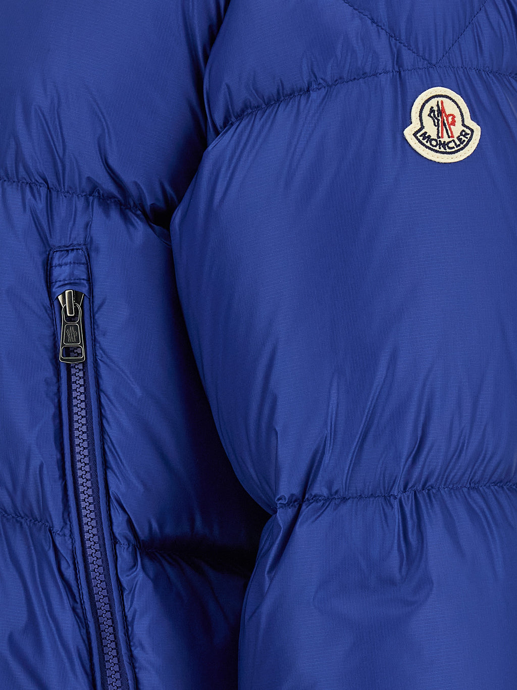 Veste longue en polyamide bleue Moncler, imperméable et padding, affichant un design moderne et élégant.