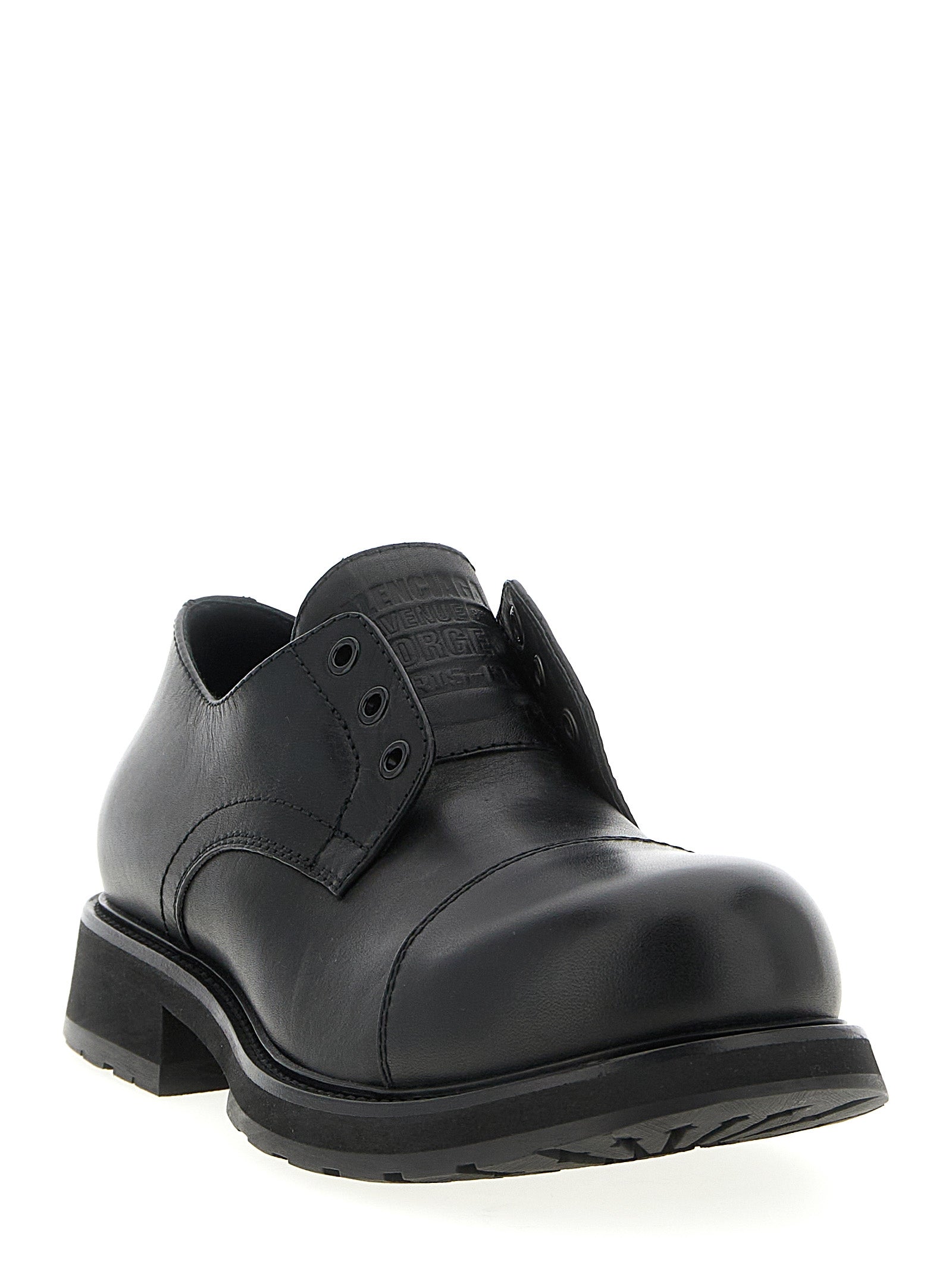 Mocassins slip-on Balenciaga en peau de taureau noire, élégants et sophistiqués, sur une surface neutre.