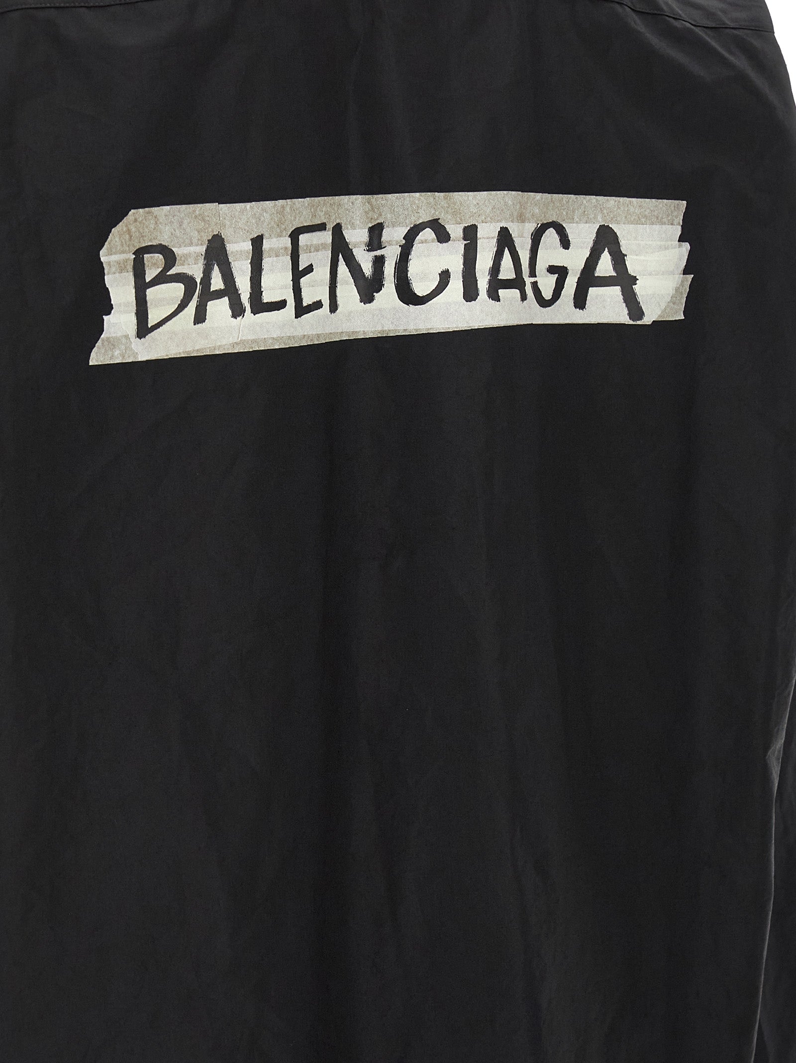 Blouse en coton noir de Balenciaga, coupe élégante, détails modernes, portée sur mannequin.