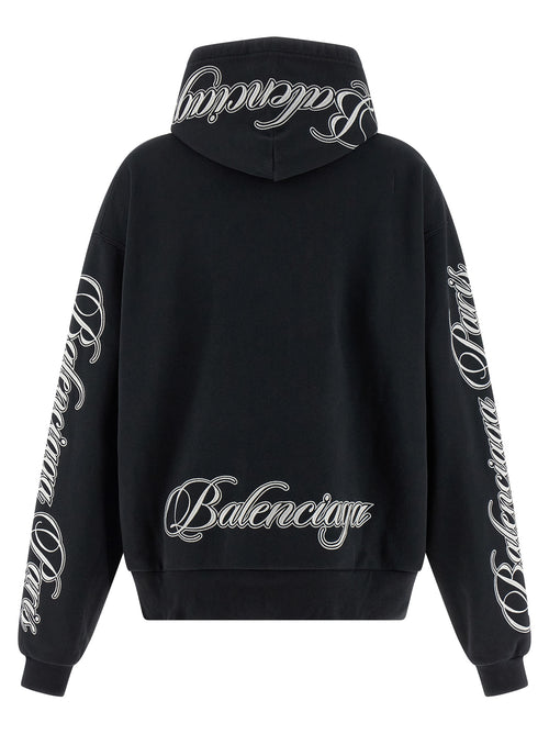 Pull à capuche en coton noir Balenciaga, décontracté avec logo discret, porté par un modèle sur fond neutre.