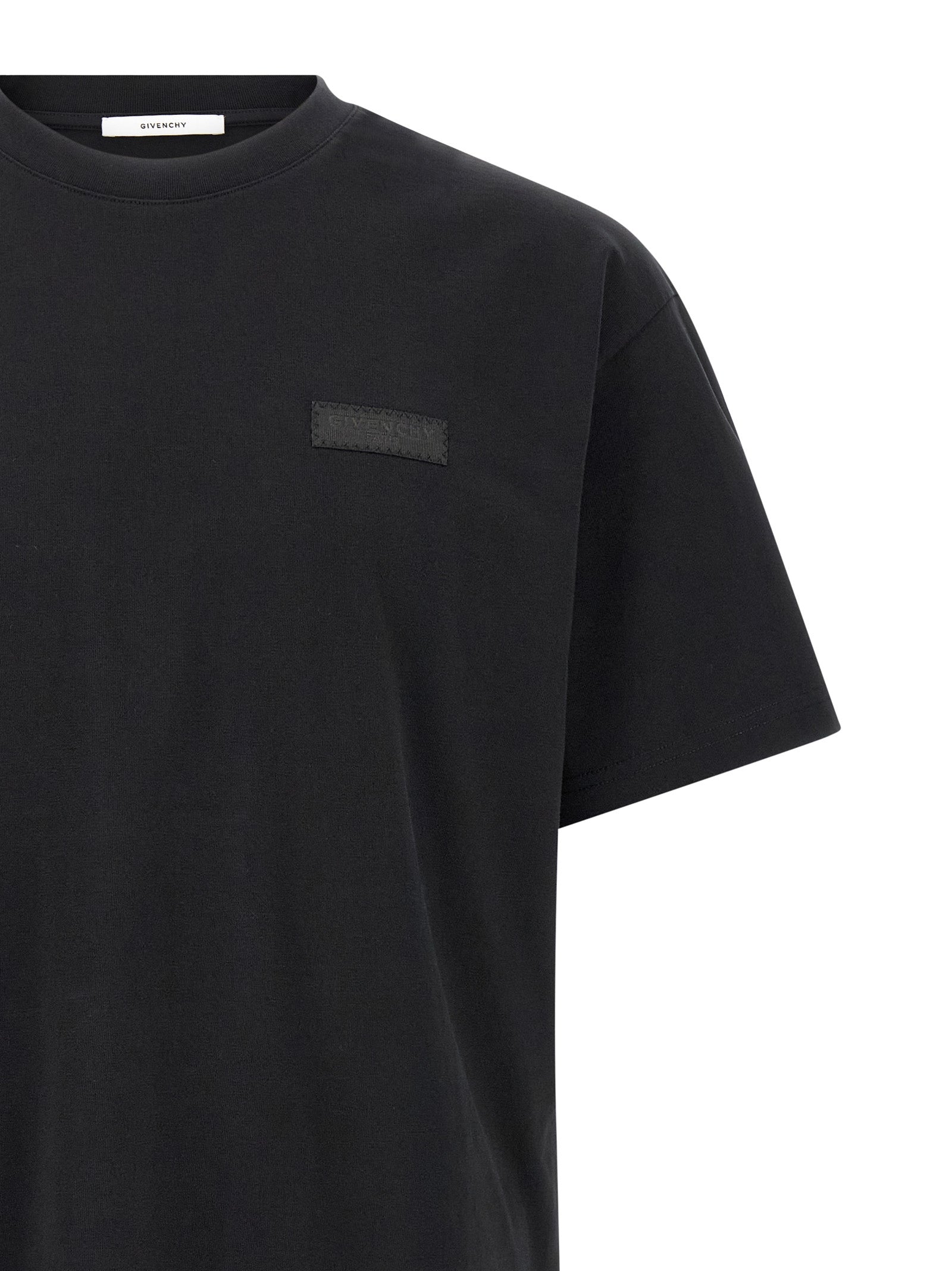 T-shirt noir en coton Givenchy, coupe classique, avec logo discret en haut à gauche, porté sur un mannequin.