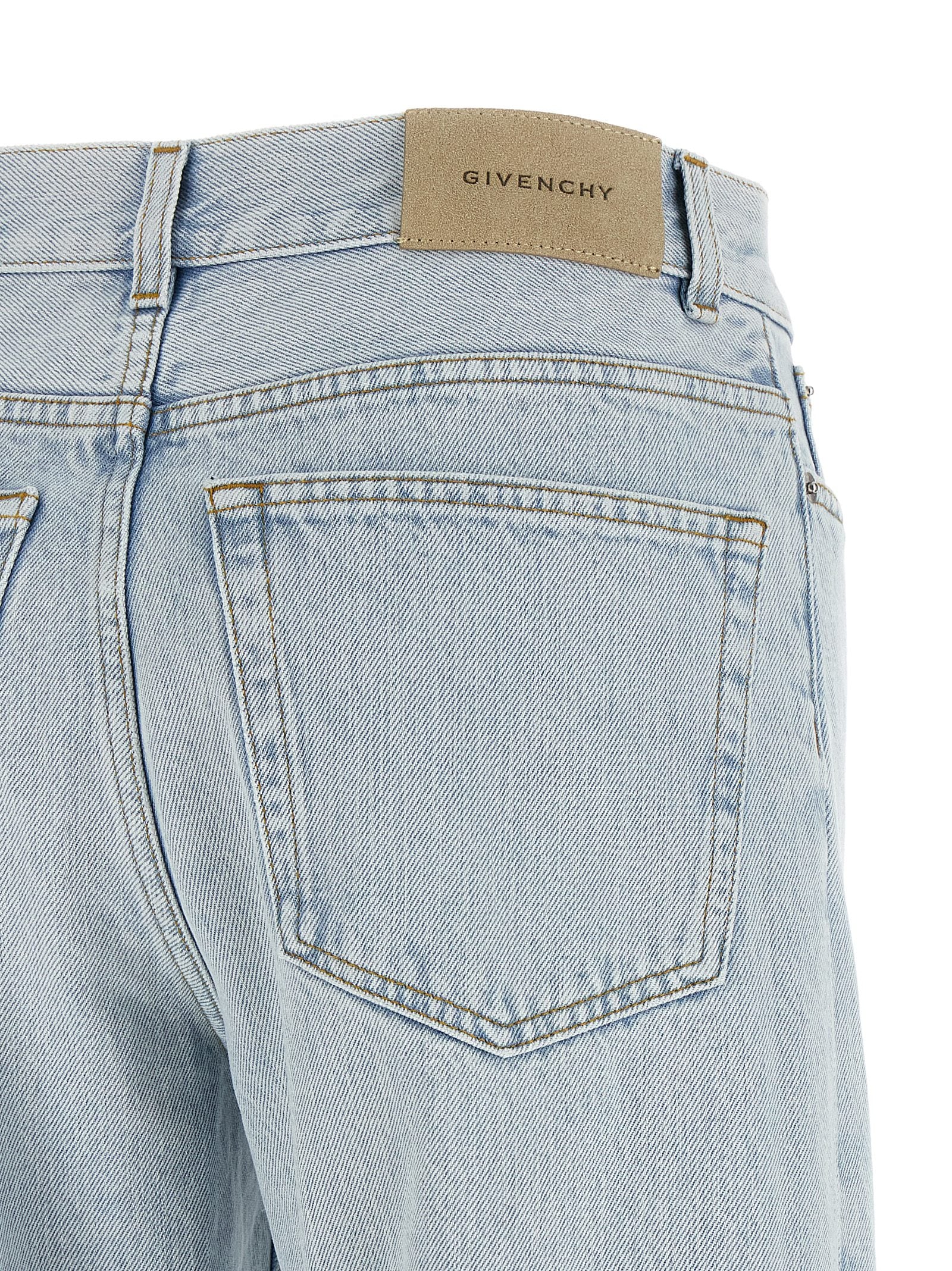 Jeans droits en coton bleu Givenchy, style classique, avec poches et fermeture à boutons visibles sur l'image.