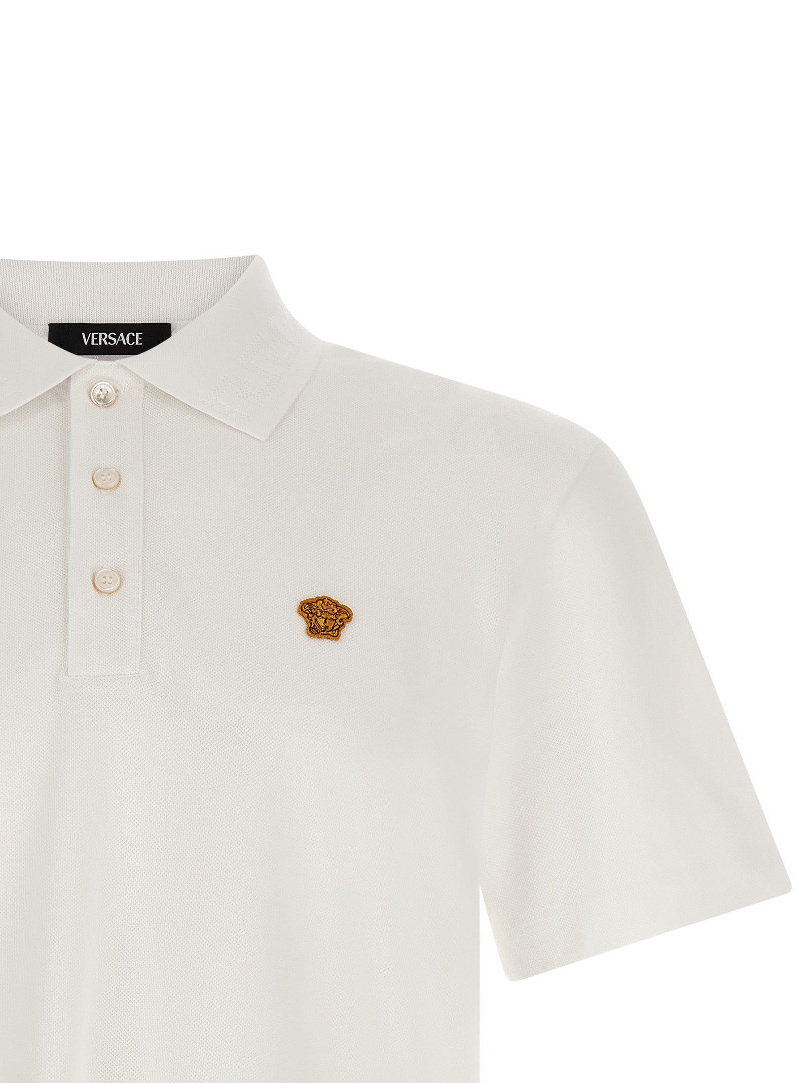 Chemise polo blanc en coton de la marque Versace, vue de face avec col et boutons visibles, tissu doux et élégant.