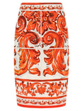 Jupe midi en soie orange de Dolce & Gabbana, élégante et fluide, portée avec un style sophistiqué et moderne.