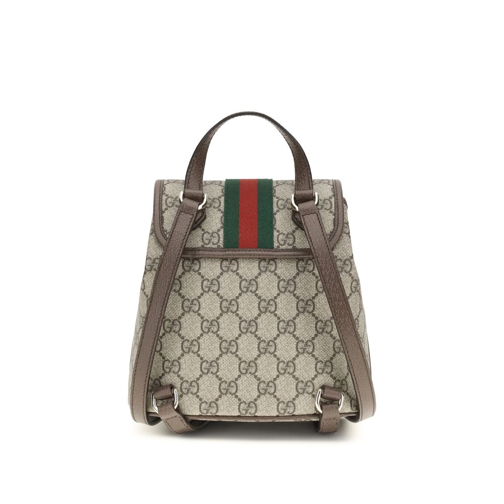 Sac à dos en tissu beige de Gucci, avec logo emblématique, fermeture éclair et poches latérales, visible de face.