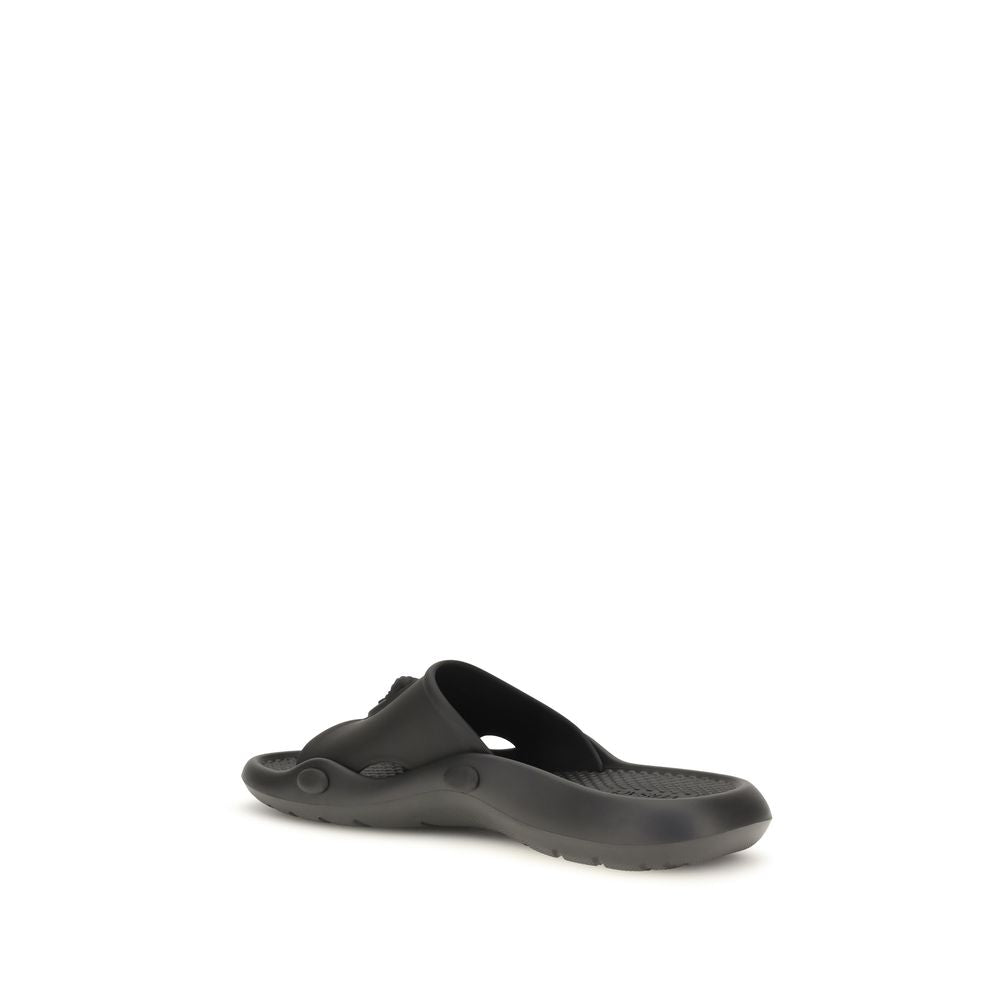 Sandales en caoutchouc noir Versace avec logo emblématique, conçues pour un style moderne et confortable.