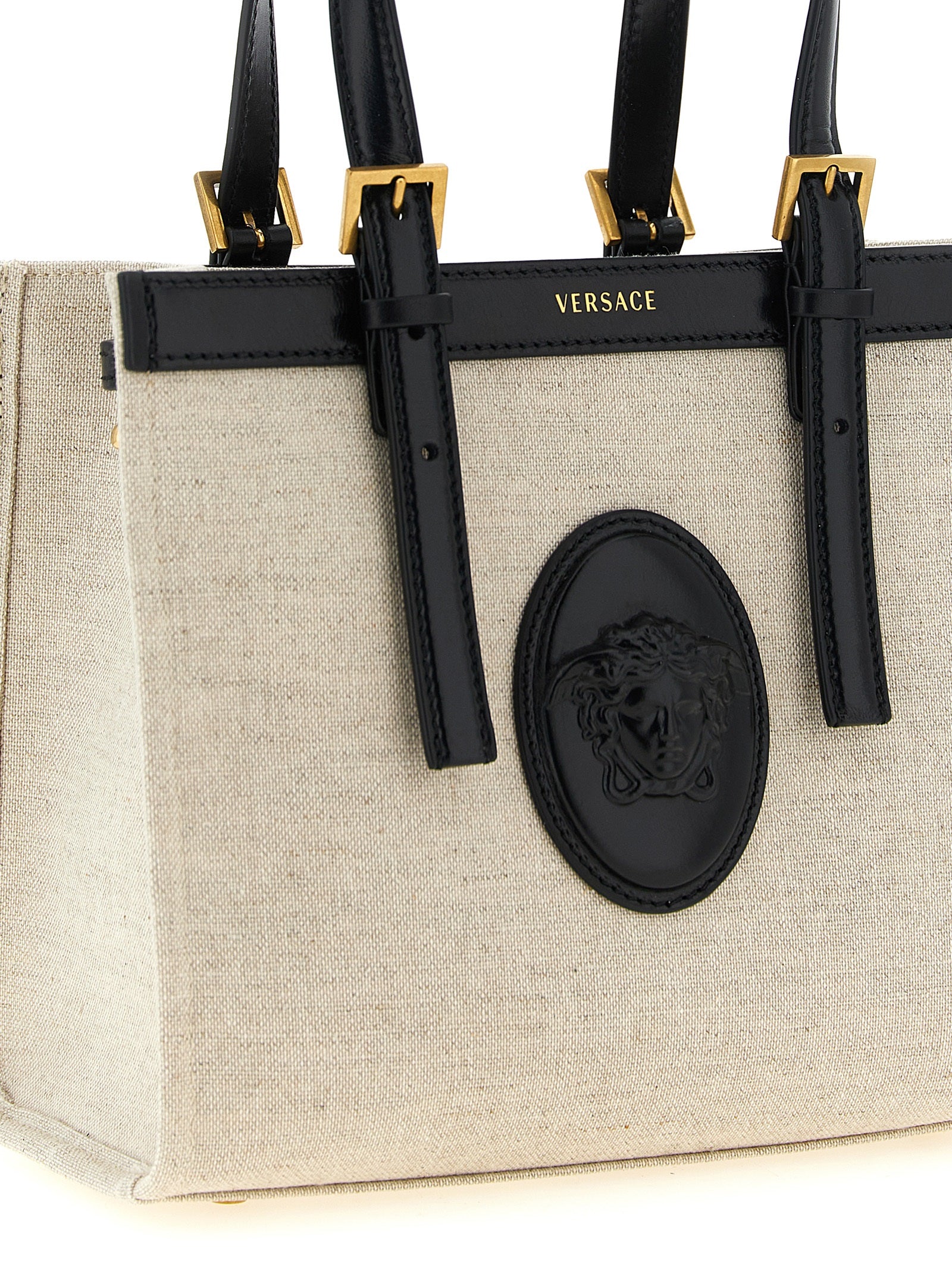 Sac cabas en lin beige de la marque Versace, avec logo emblématique et poignées en cuir, pour un style élégant et pratique.