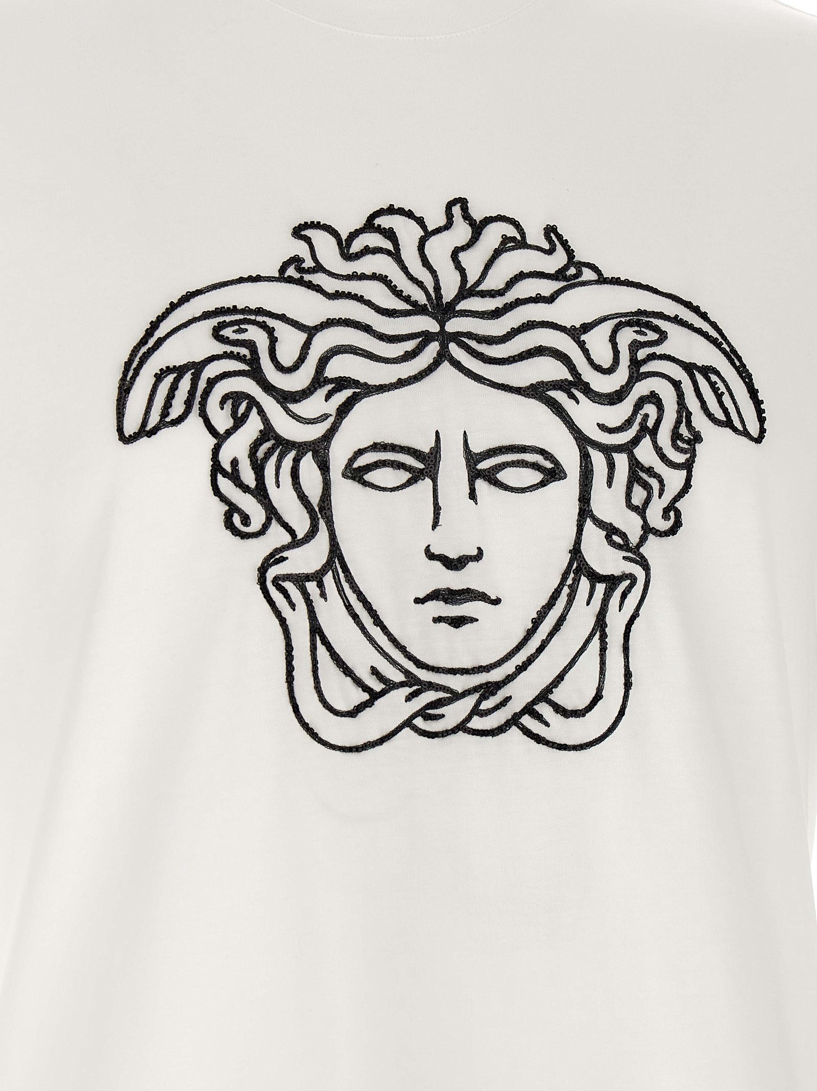 T-shirt en coton bicolore Versace, coupe classique avec logo emblématique sur la poitrine, porté par un mannequin.