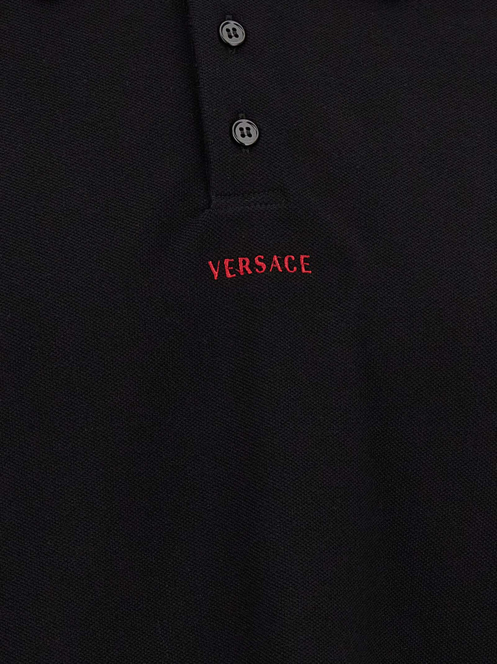 Chemise polo noire en coton de la marque Versace, avec logo distinctif et design élégant, sur un fond neutre.