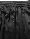 Jupe en satin noire Dolce & Gabbana avec bordure en dentelle et fente latérale élégante.