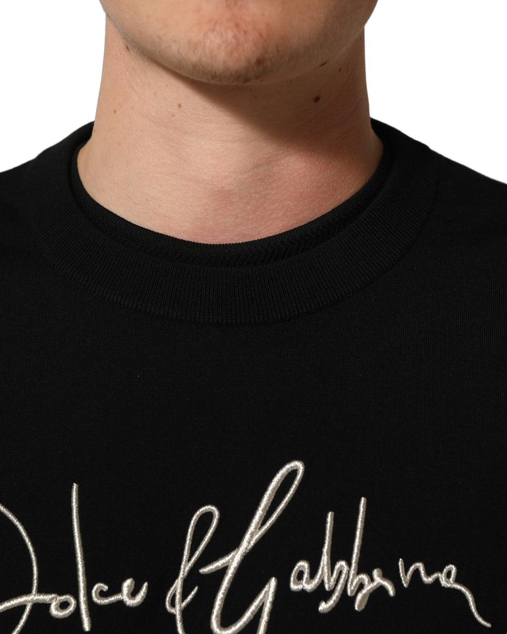 Pull homme Dolce & Gabbana noir à col rond avec broderies DG, chic et confortable, porté sur un mannequin.