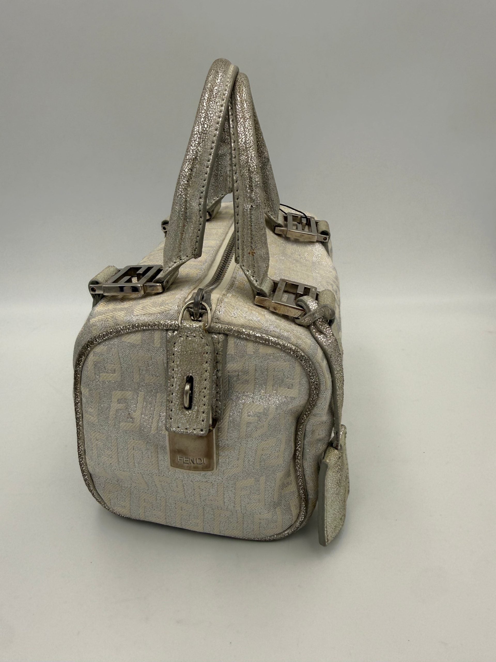 Sac à main Fendi Mini Bauletto FF Zucchino en lamé, avec motif emblématique et poignée en cuir, visible en gros plan.