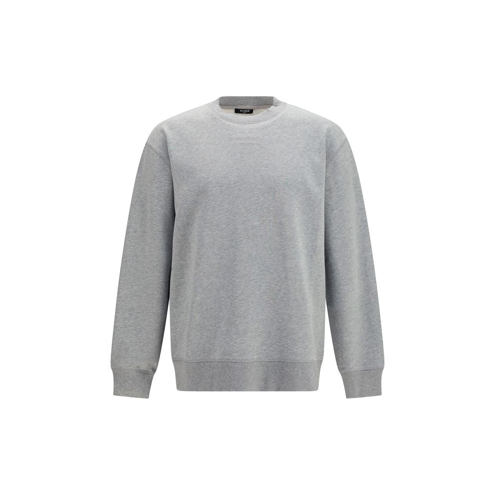 Sweat-shirt gris en coton de Balmain, style décontracté, avec logo discret, porté sur un modèle.