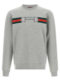 Sweat-shirt gris en coton de la marque Gucci, avec logo discret visible sur le devant, porté dans un style décontracté.