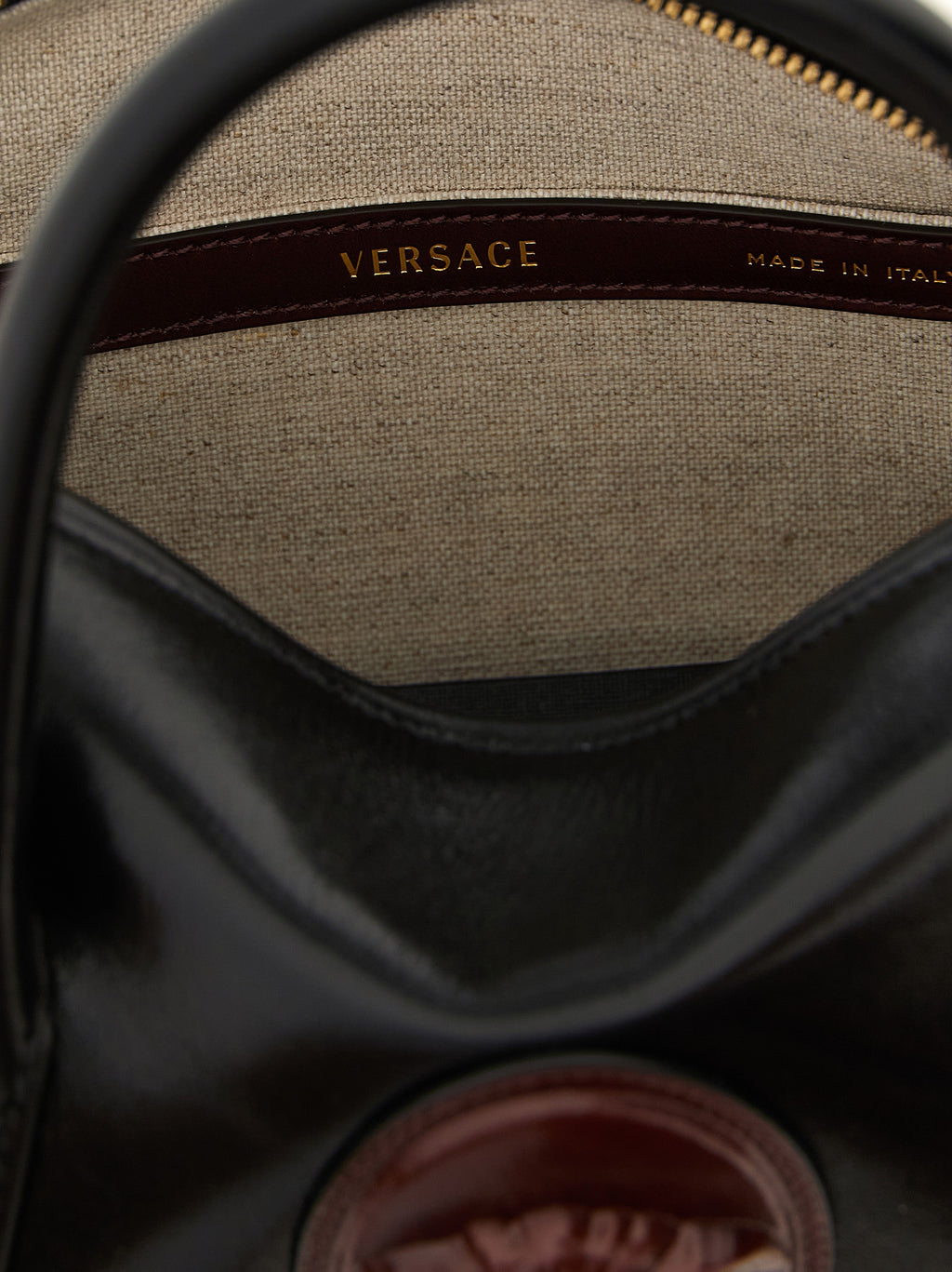Sac à main en cuir de veau noir de Versace, élégant et sophistiqué, avec détails emblématiques de la marque.