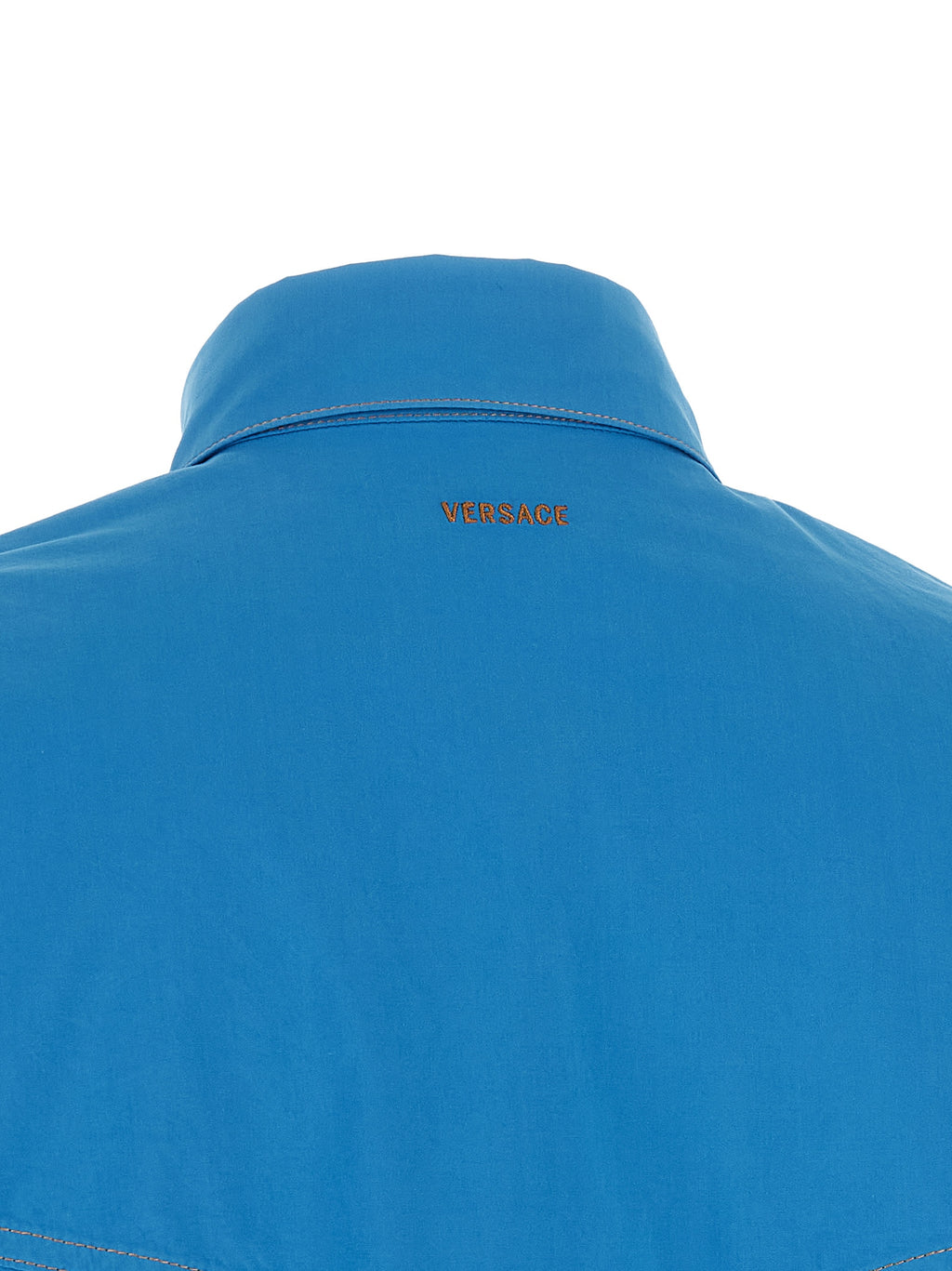 Blouse en coton bleu Versace, coupe élégante et détails sophistiqués visibles sur la photo.