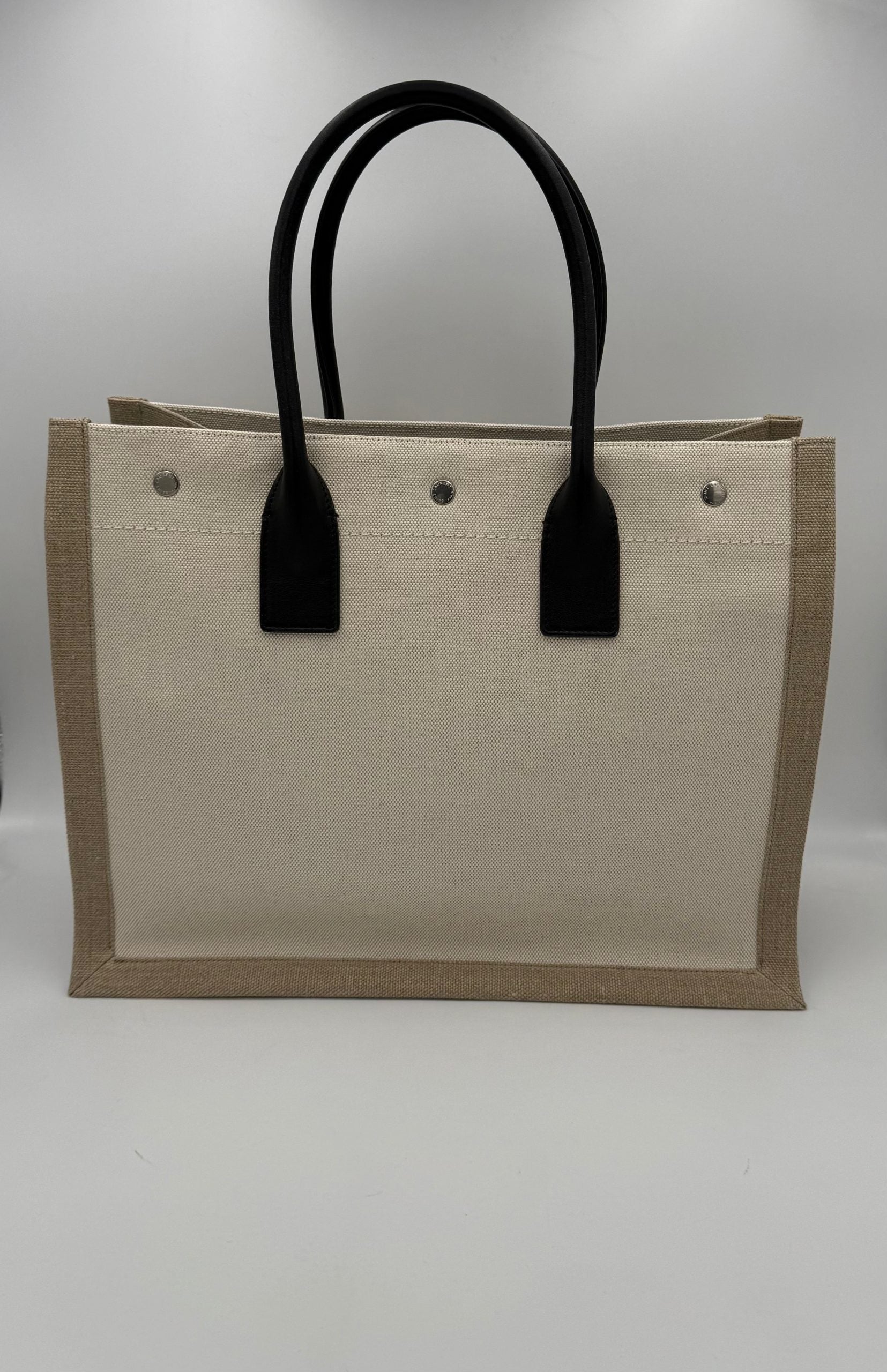 Sac moyen Saint Laurent Rive Gauche en toile noire avec poignées en cuir et logo doré.