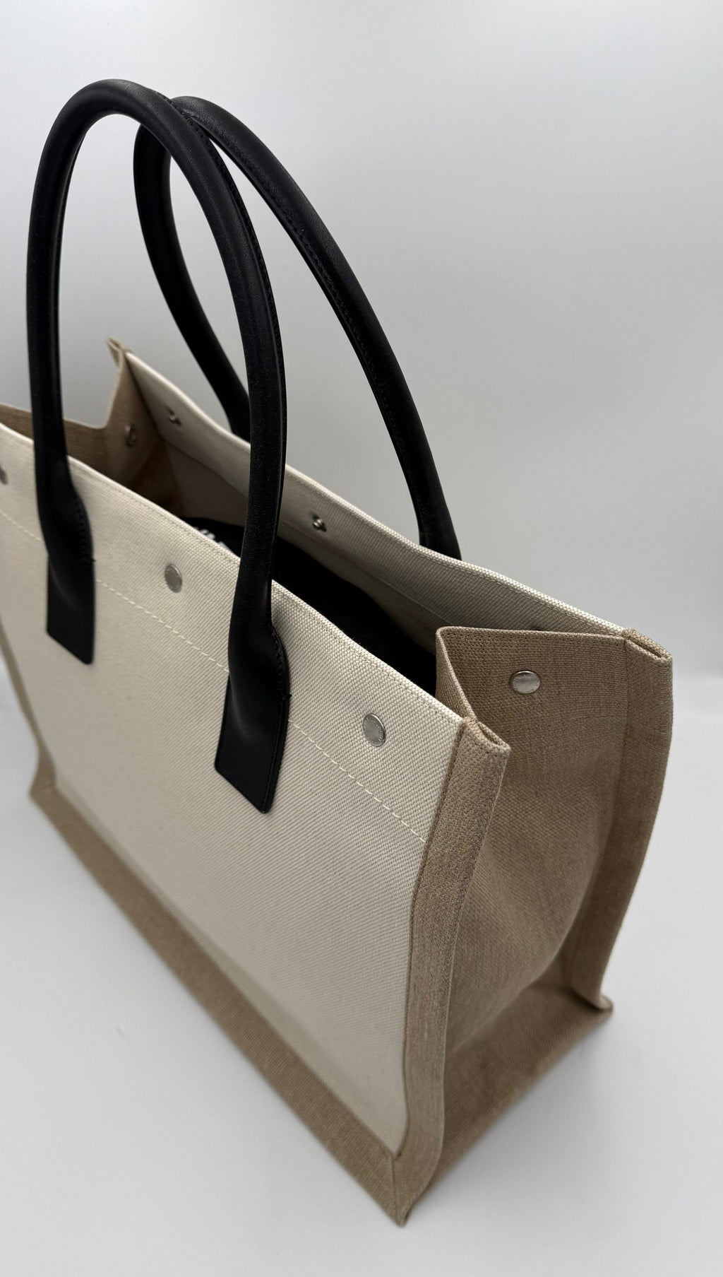Sac cabas moyen Saint Laurent Rive Gauche en cuir noir avec logo or, porté sur l'épaule, élégant et sophistiqué.