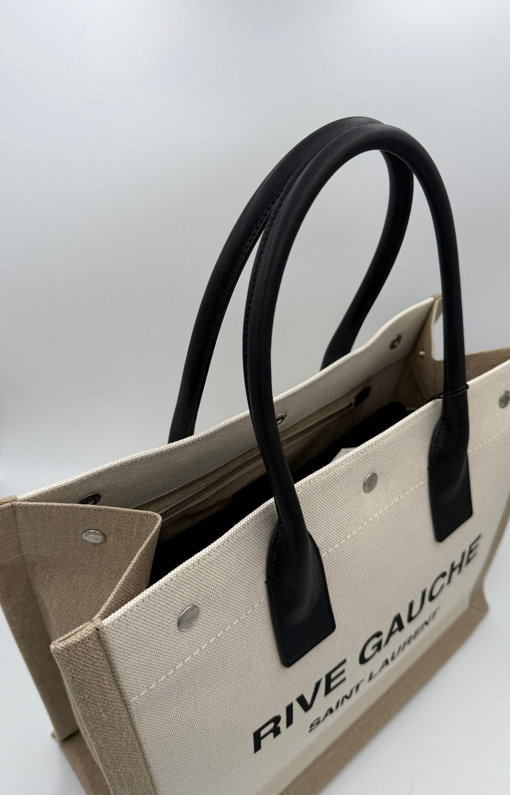 Sac cabas moyen Saint Laurent Rive Gauche en cuir noir avec logo emblématique, porté sur l'épaule.