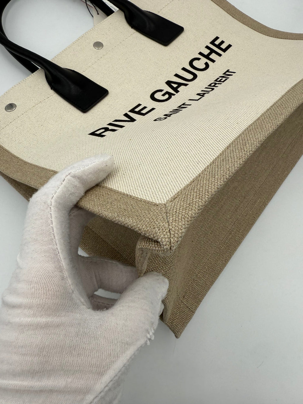 Sac à main medium Saint Laurent Rive Gauche en cuir noir avec poignées et logo doré visible sur l'image.