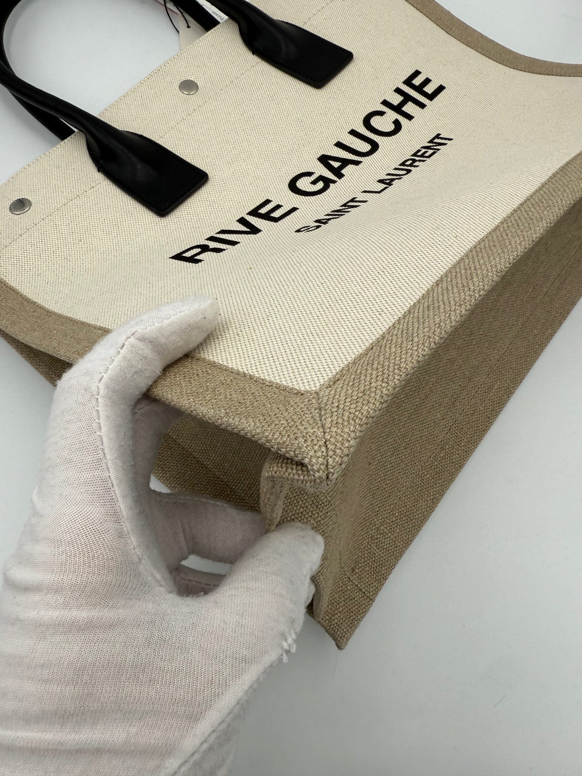 Sac à main medium Saint Laurent Rive Gauche en cuir noir avec poignées et logo doré visible sur l'image.