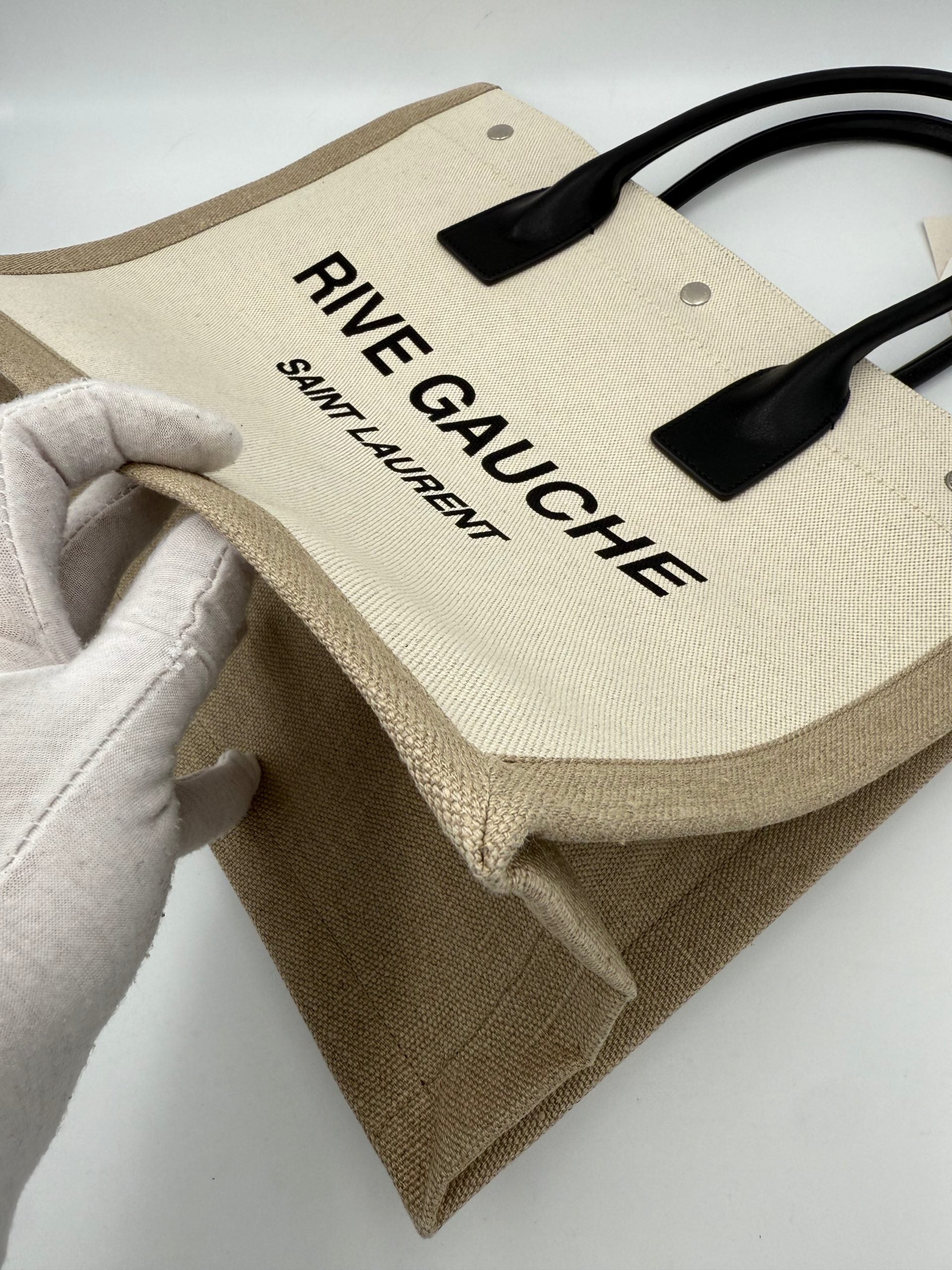 Sac cabas moyen Saint Laurent Rive Gauche en cuir noir avec logo doré, porté sur l'épaule.