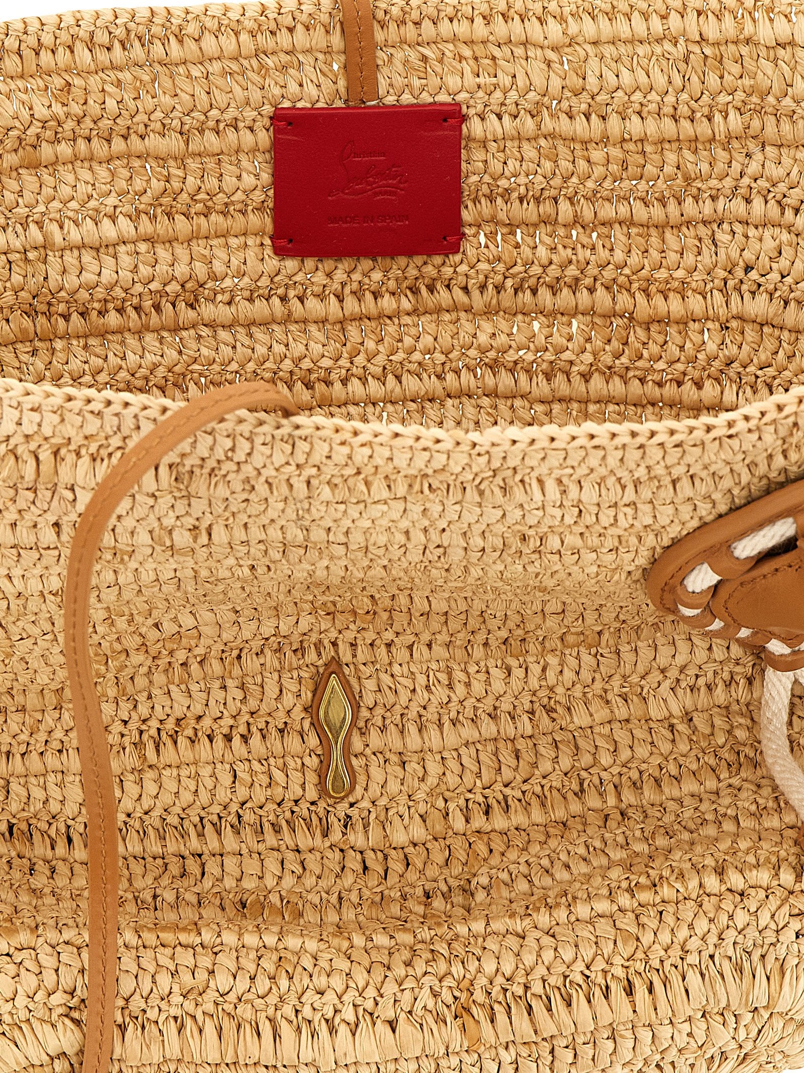 Sac à main Christian Louboutin en raffia beige avec poignées, élégant et idéal pour un look estival.