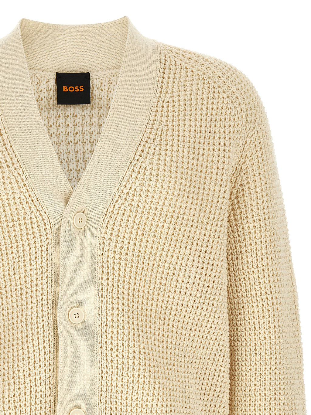Cardigan en coton beige de la marque Hugo Boss, doux et élégant, porté sur un modèle, détails visibles sur l'image.