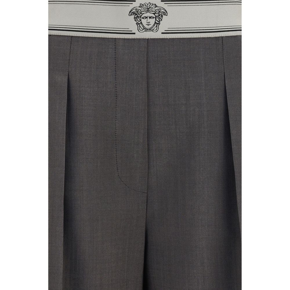 Pantalons gris en laine Versace Oves Aries avec détails sophistiqués et coupe élégante, visibles dans l'image.