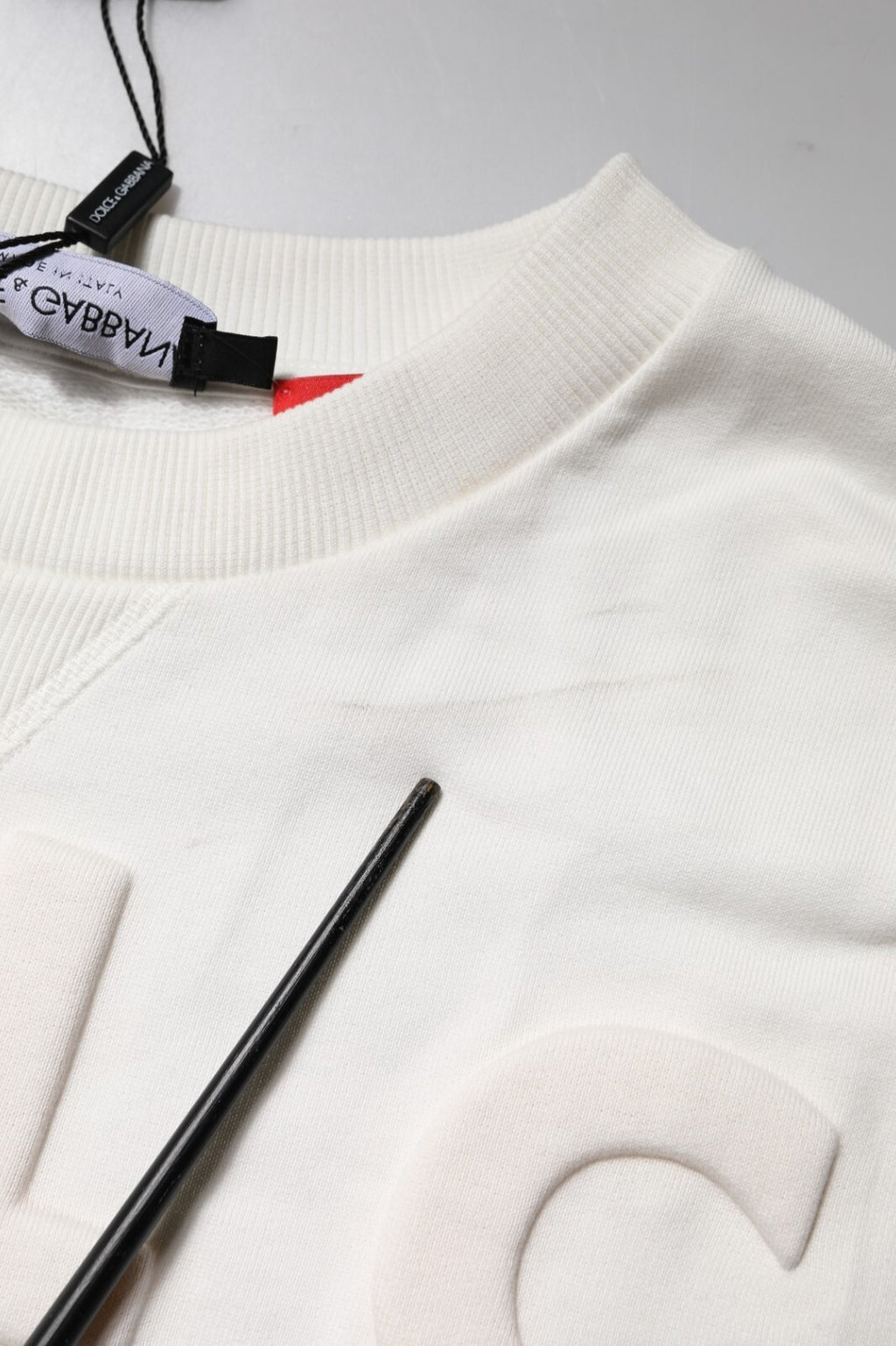 Pull en coton blanc Dolce & Gabbana avec logo embossé, col rond et style décontracté visible sur l'image.