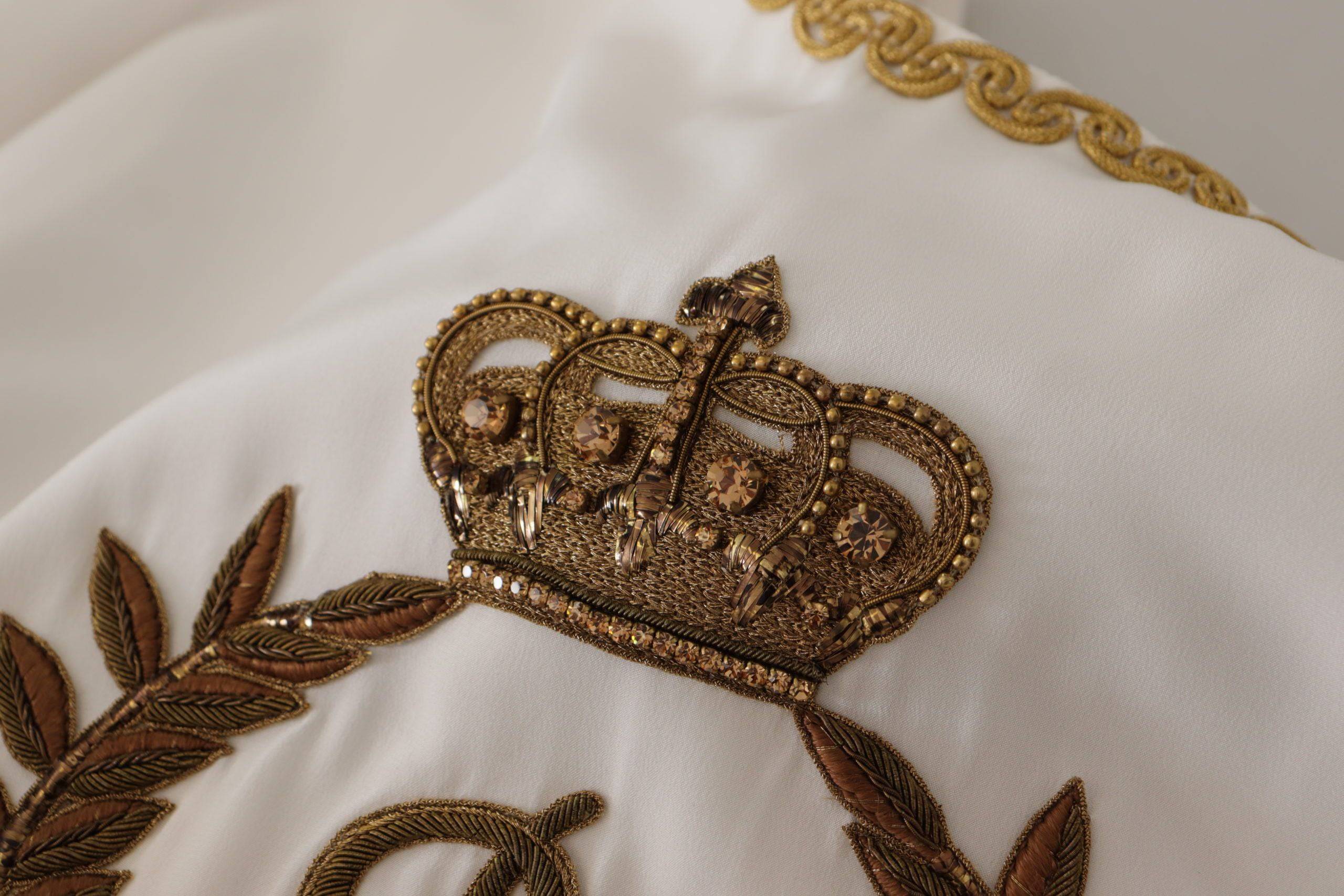 Blouse en soie blanche Dolce & Gabbana avec ornement DG, couronne en cristal, style élégant et sophistiqué.