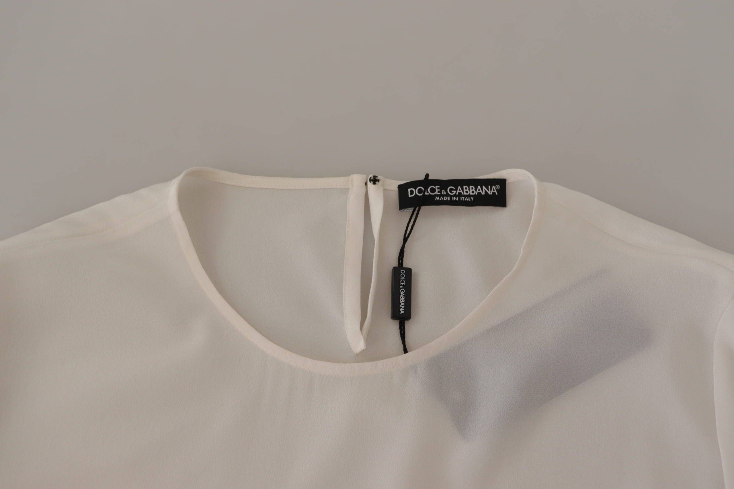 Chemise longue en soie blanche Dolce & Gabbana avec logo DG brodé et manches longues, élégante et raffinée.