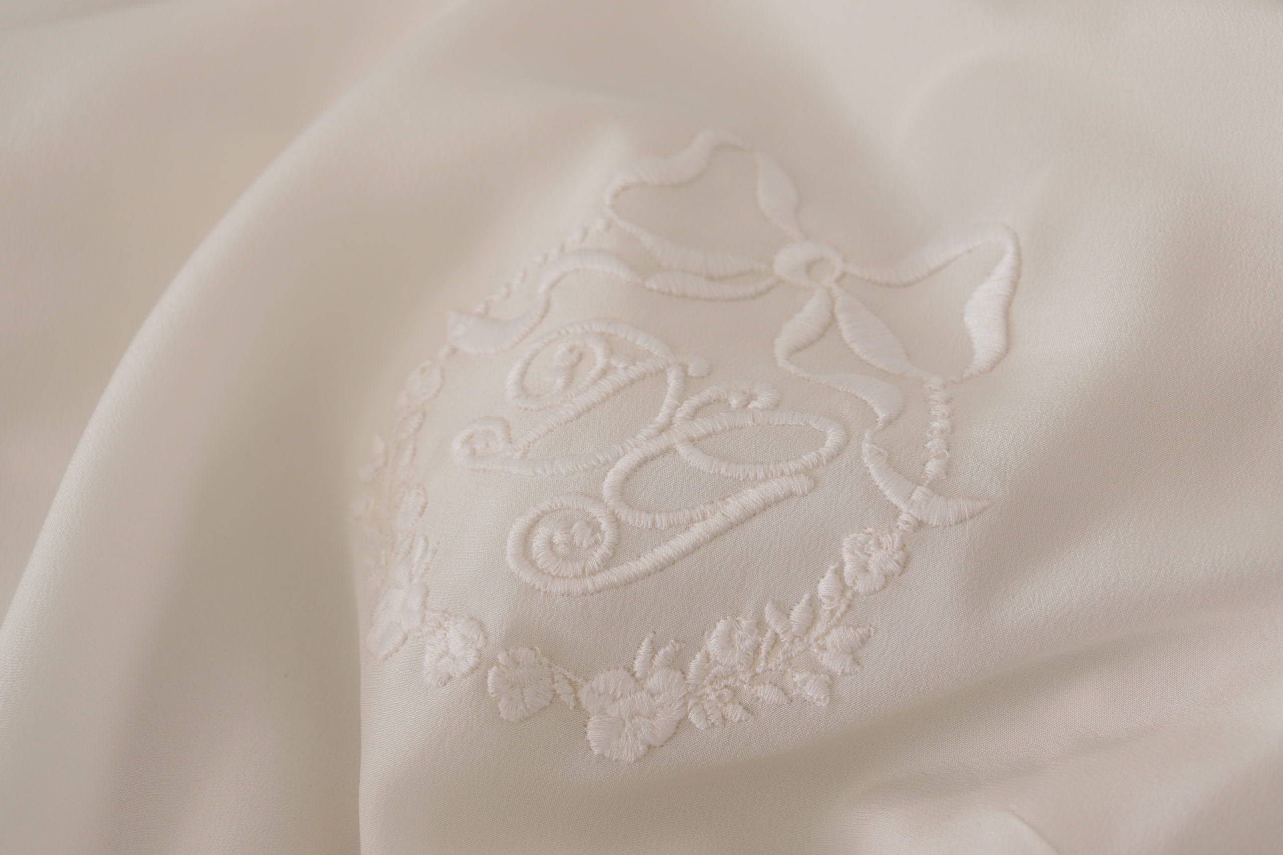 Chemise longue en soie blanche Dolce & Gabbana avec logo DG brodé et manches longues, élégante et sophistiquée.
