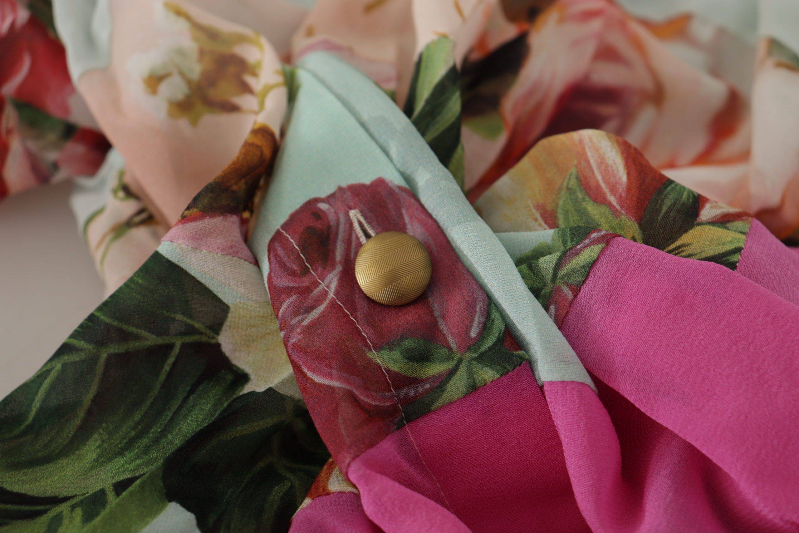 Blouse Dolce & Gabbana à col ascot avec patchwork floral multicolore, design élégant et détails colorés.