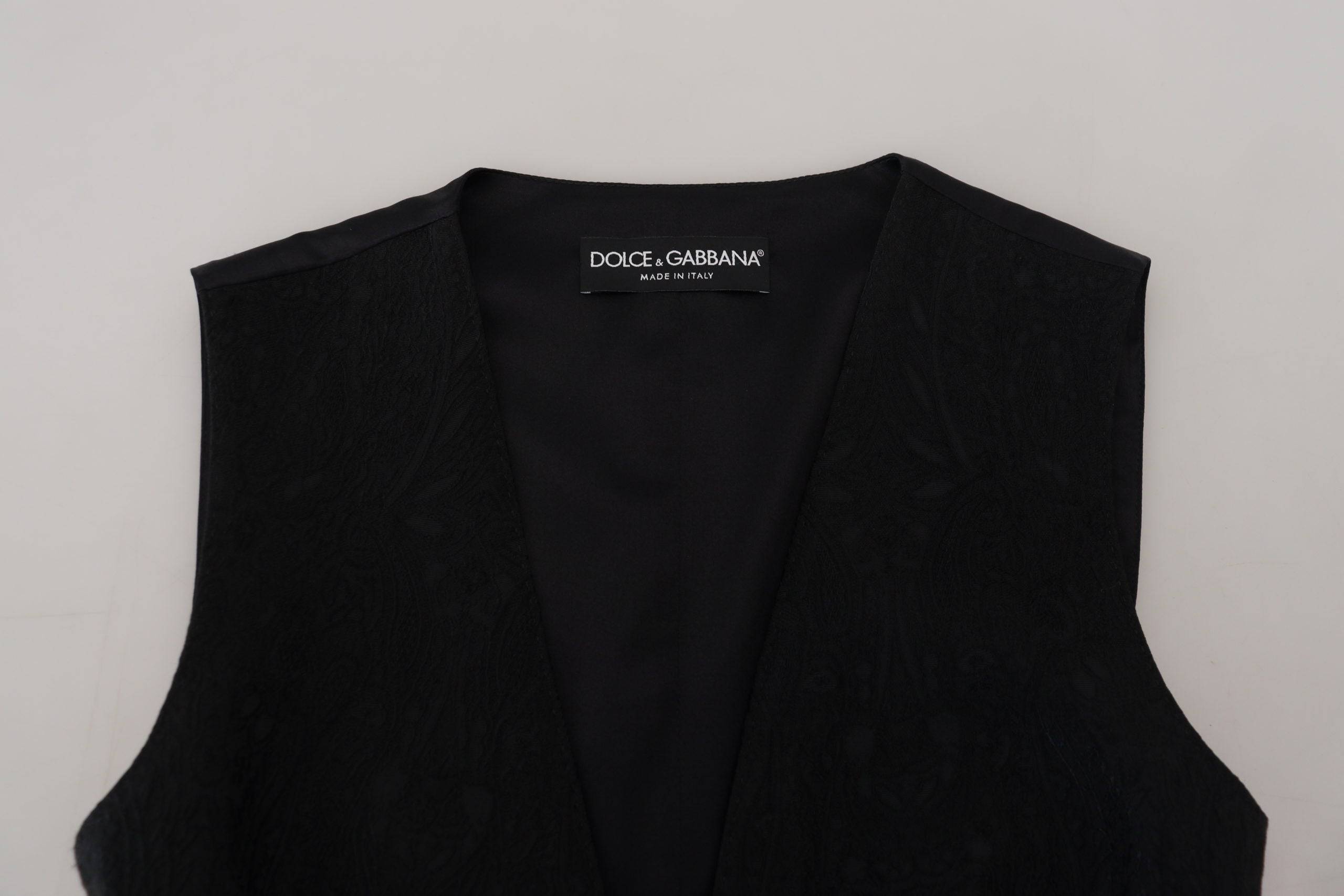 Gilet sans manches noir en brocart de Dolce & Gabbana avec boutons, élégant et texturé, porté sur un fond neutre.