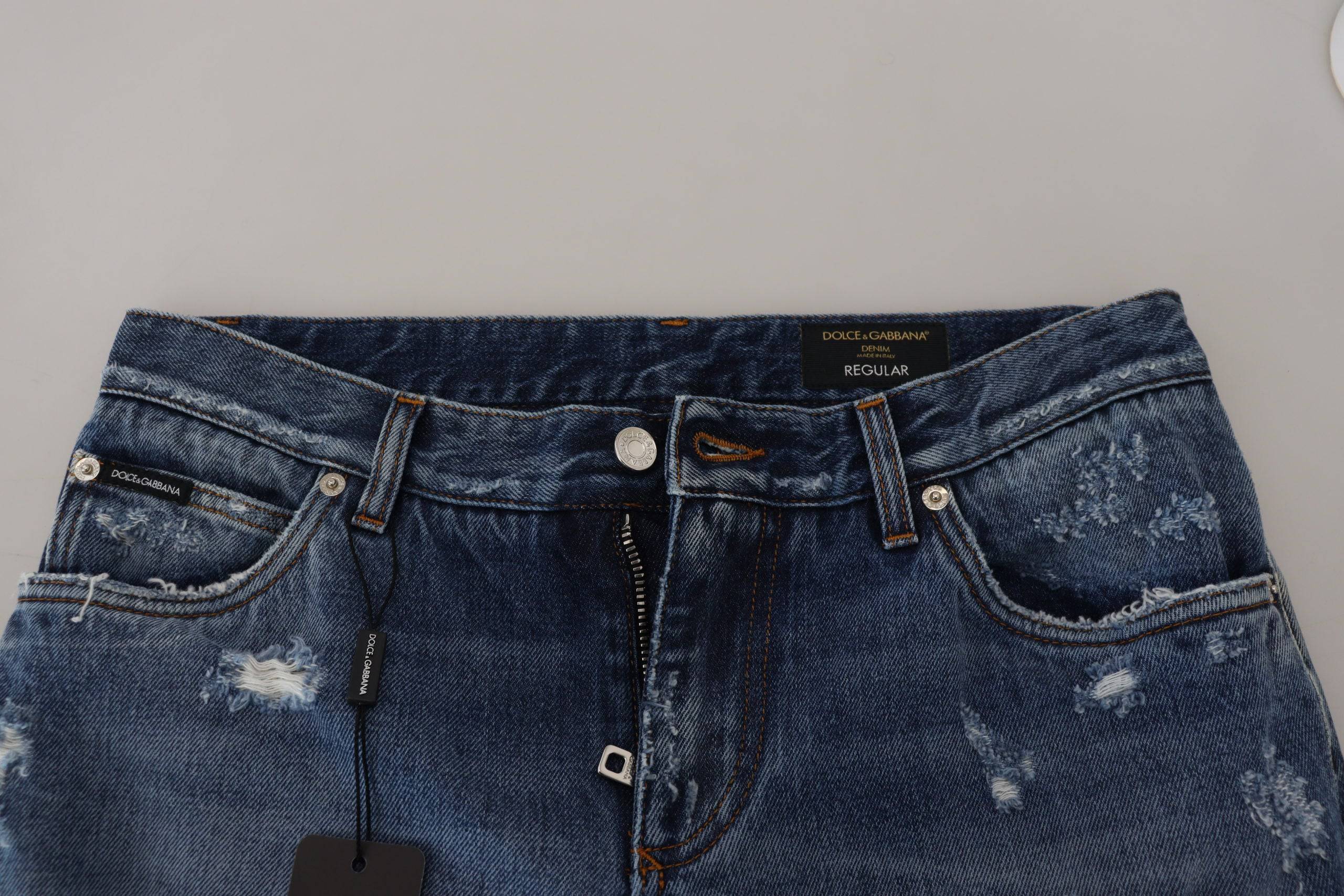Jeans en denim bleu pour homme de Dolce & Gabbana, coton tacheté avec détails usés et déchirés.