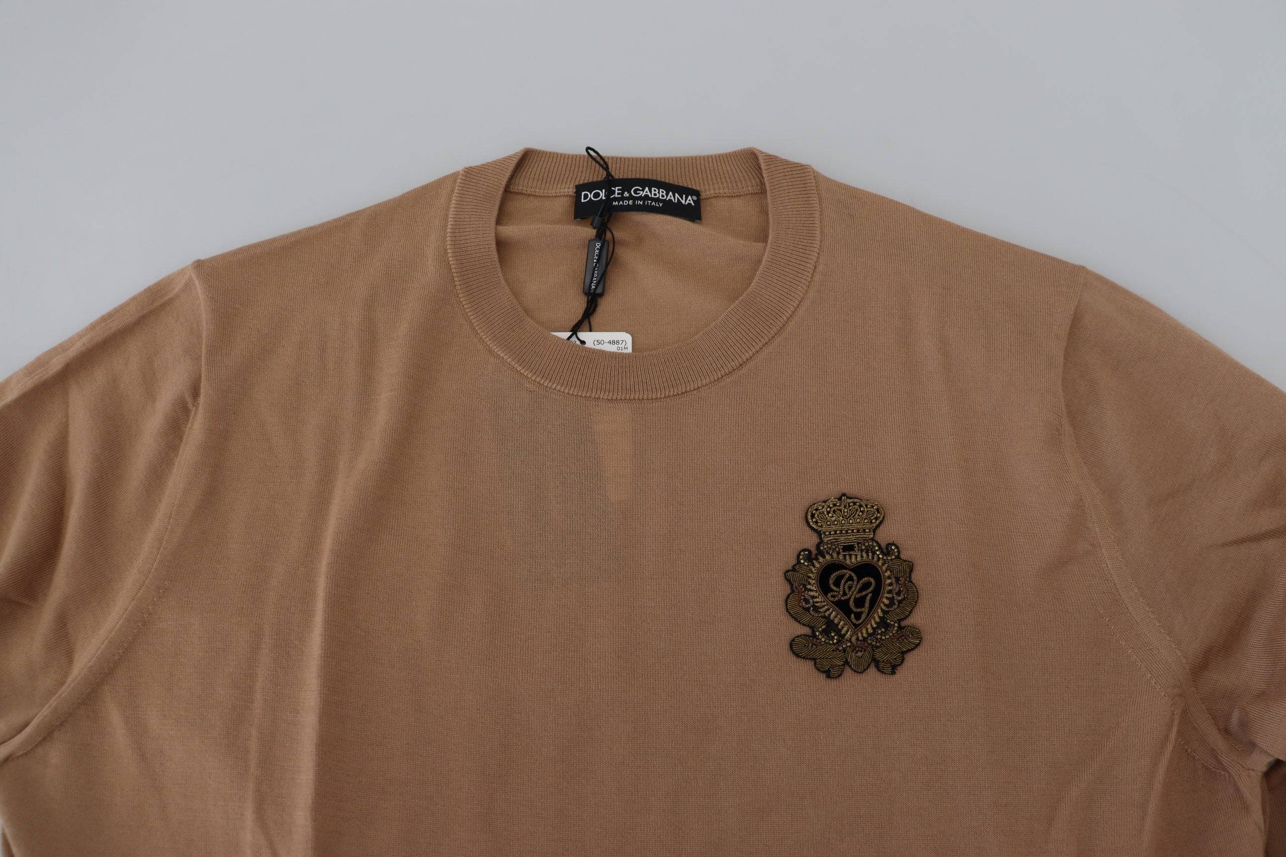 Pull-over en cachemire beige Dolce & Gabbana avec logo couronne, doux, élégant et confortable, visible en détail.