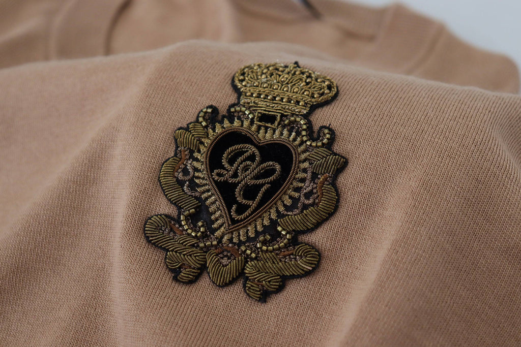 Pull Dolce & Gabbana en cachemire beige avec logo couronne, coupe classique et détails élégants, porté sur mannequin.