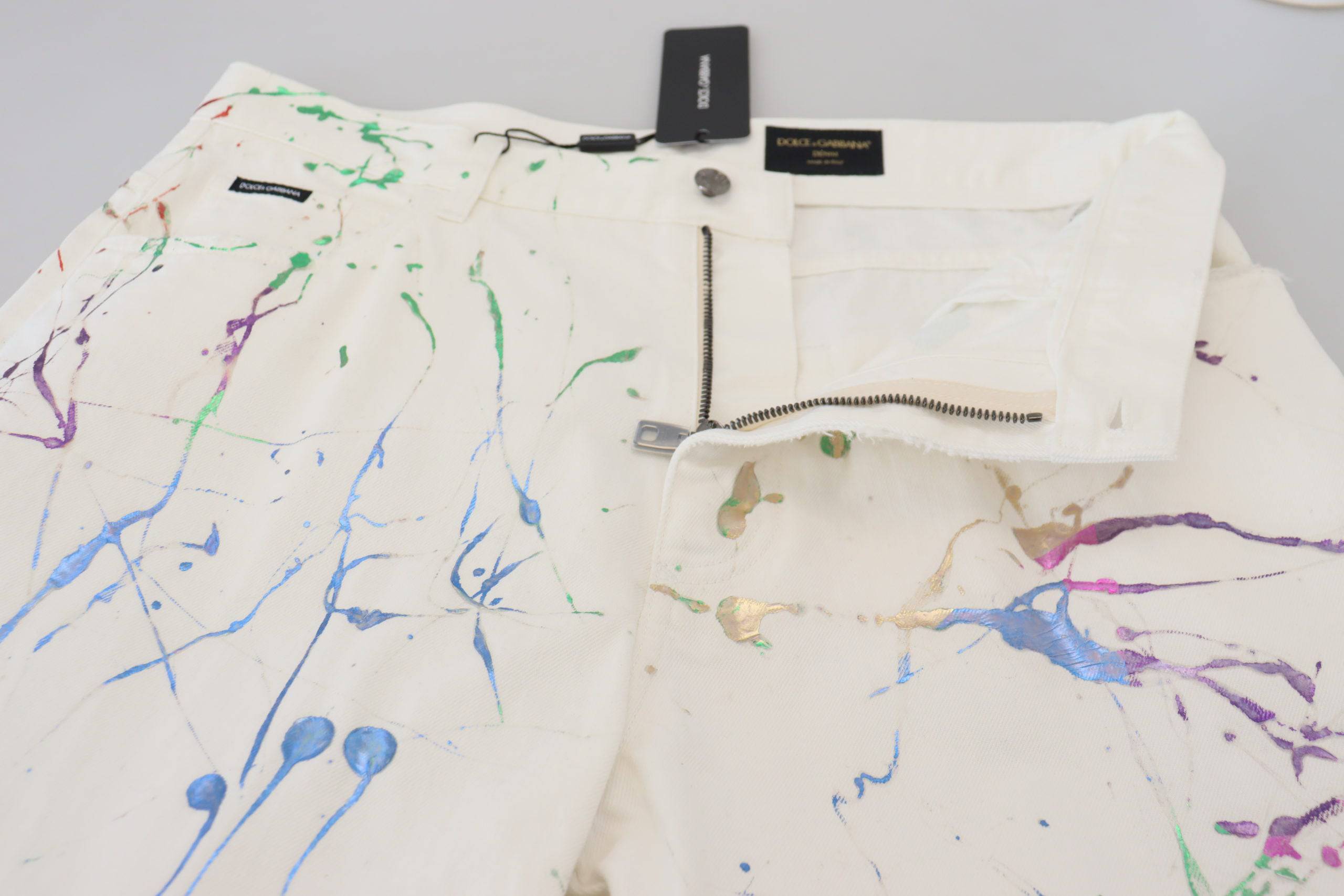 Pantalon en denim blanc Dolce & Gabbana avec éclaboussures de couleurs et coupe décontractée, vue de face.