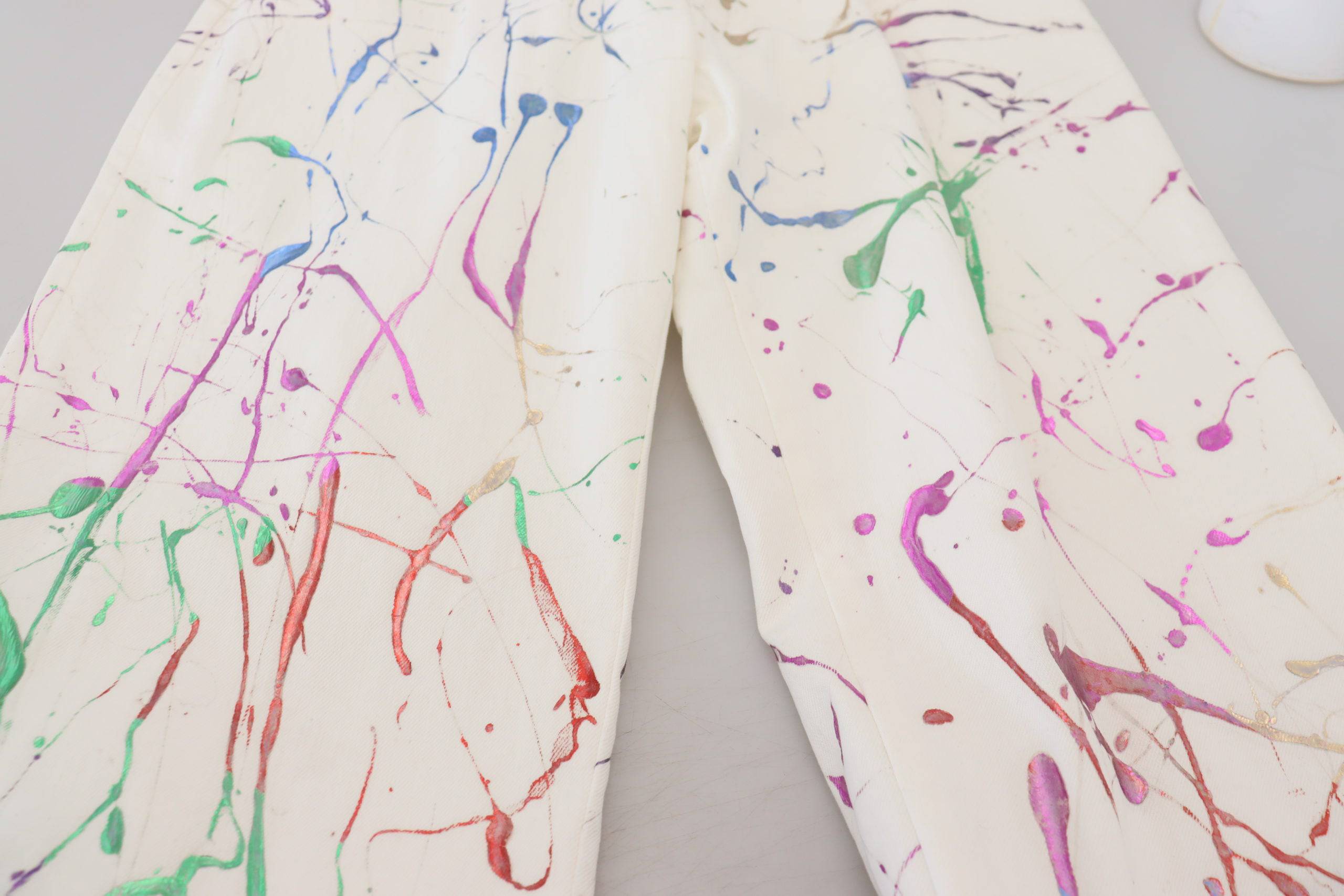 Pantalons en denim blanc Dolce & Gabbana avec imprimé coloré en éclaboussures de peinture, coupe classique.