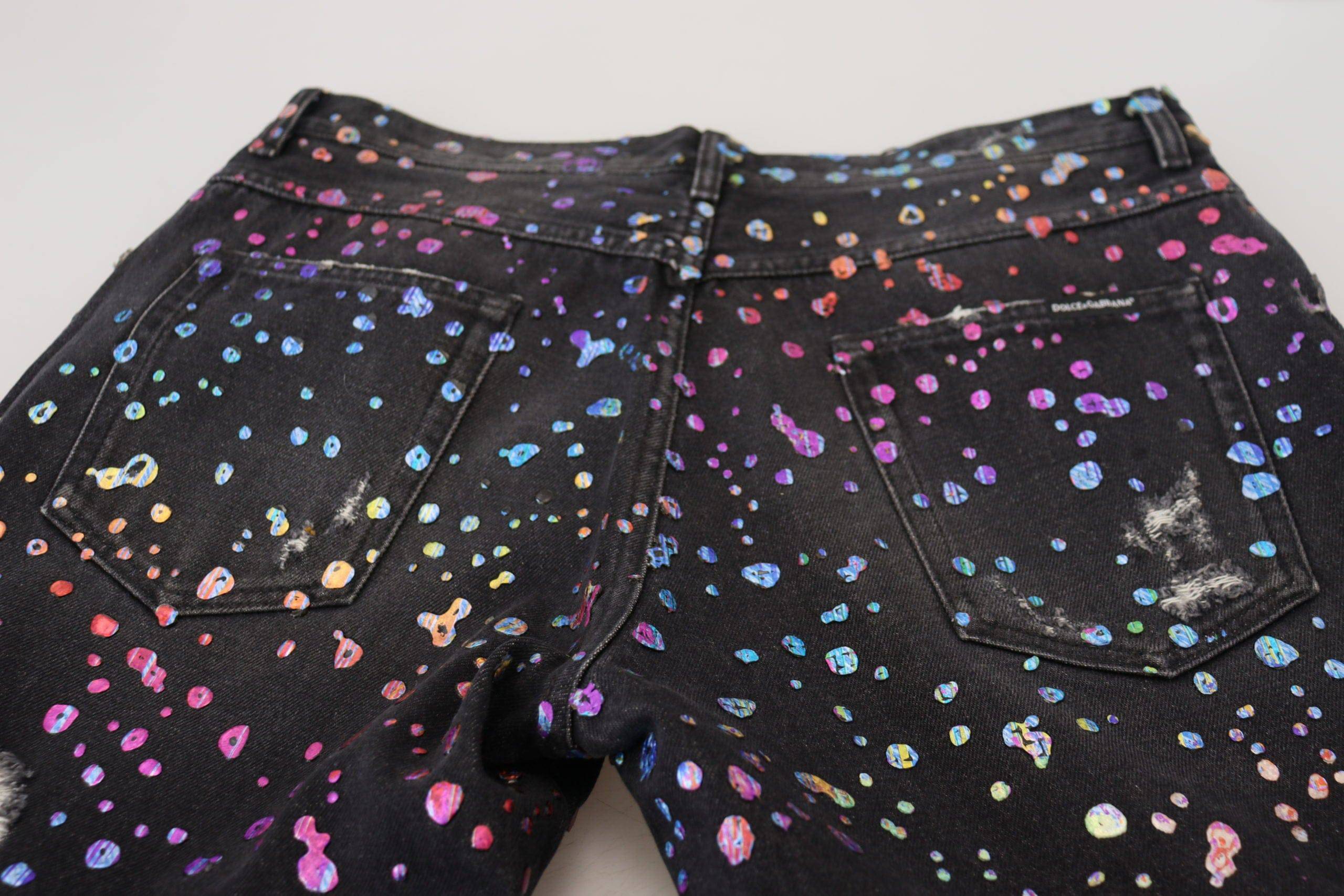 Jeans déchirés en denim noir à imprimé multicolore de Dolce & Gabbana, style tendance et détails décontractés.