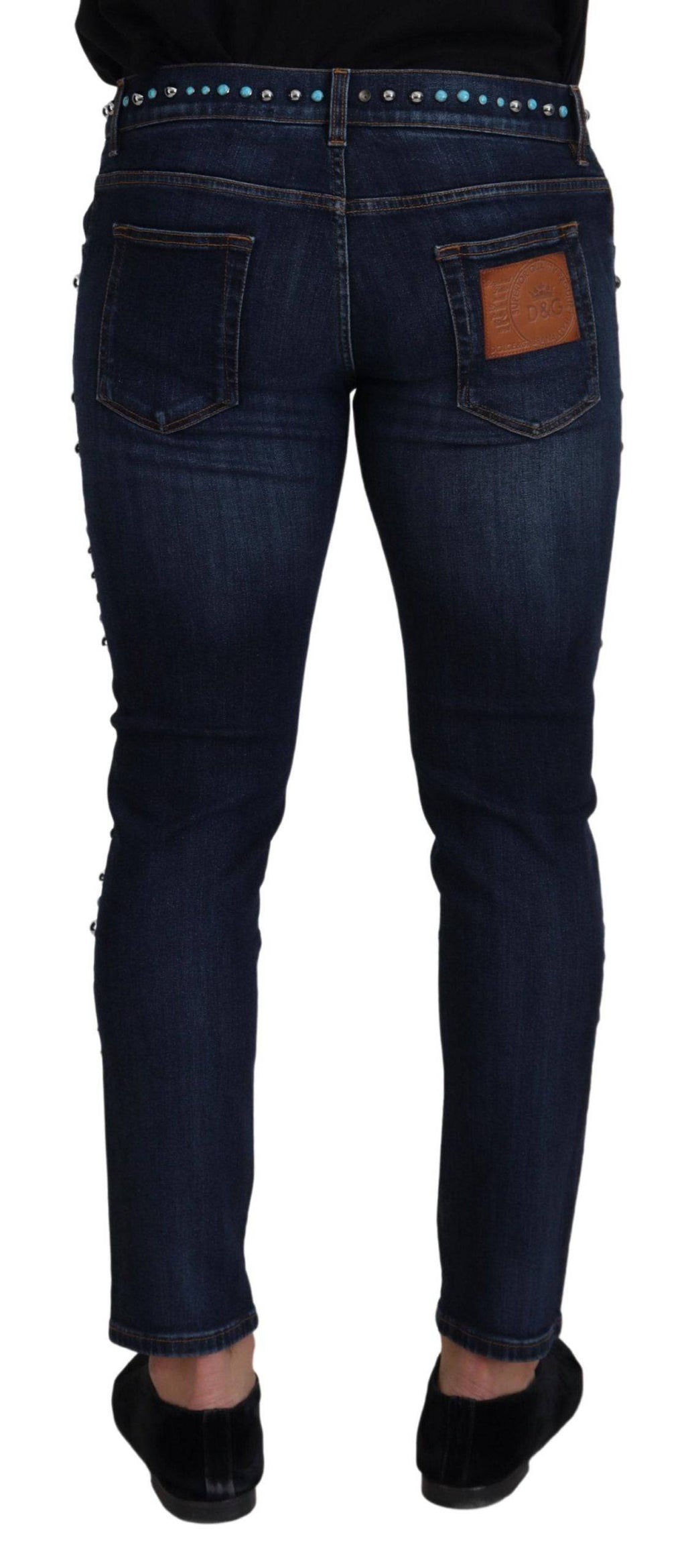 Jeans délavés en coton bleu Dolce & Gabbana avec studs, taille basse et coupe moderne, visibles sur l'image.
