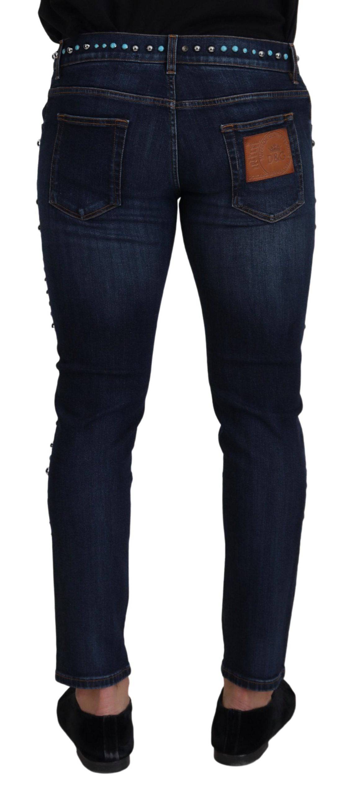 Jeans délavés en coton bleu Dolce & Gabbana avec studs, taille basse et coupe moderne, visibles sur l'image.