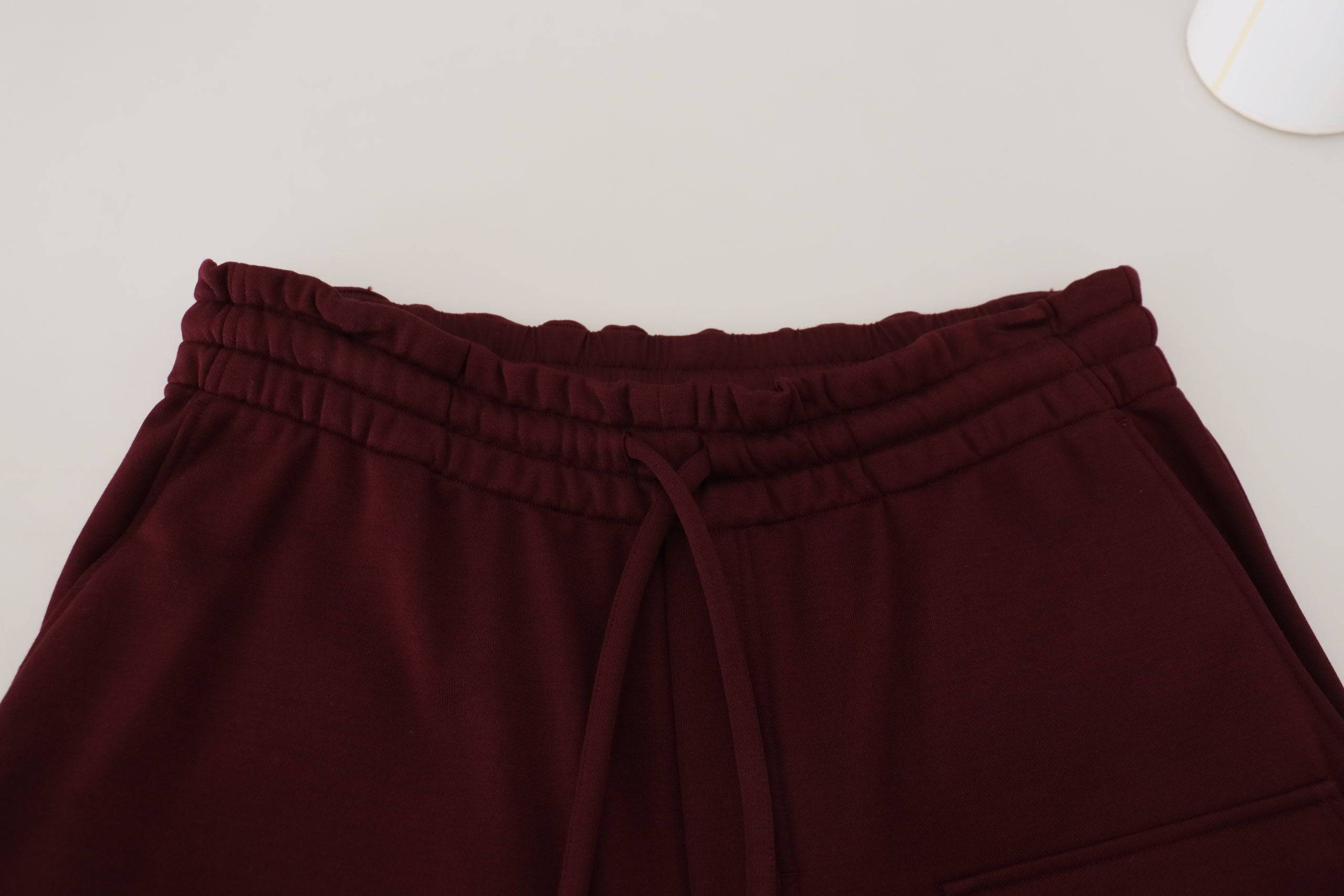 Shorts bermuda cargo pour hommes Dolce & Gabbana en bordeaux, style décontracté avec poches latérales et bouton.